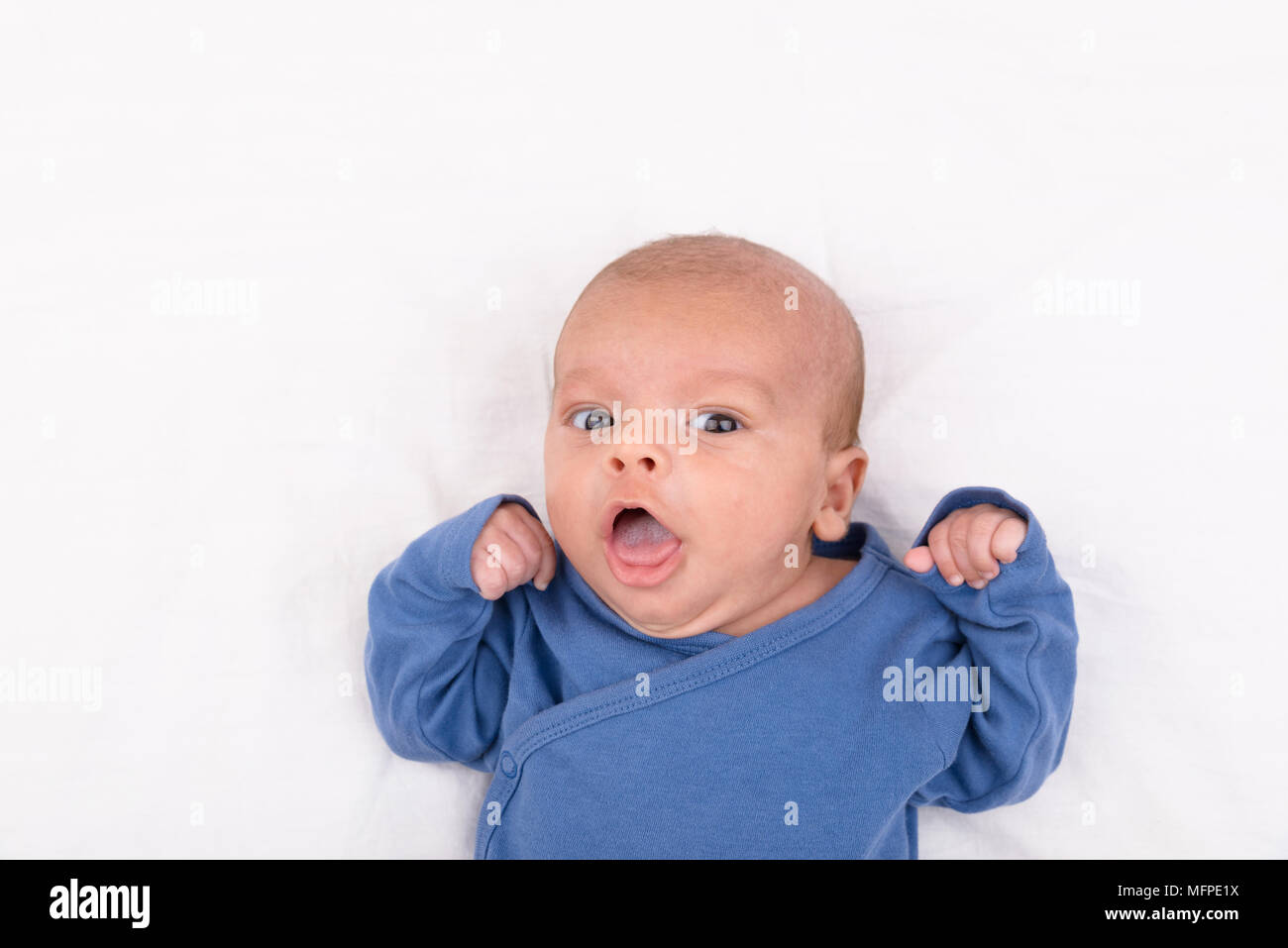 Cute eurasischen neugeborenes Baby Boy trägt ein blaues baby bodysuit auf weißem Blatt, und wenn man die Kamera, mit Kopie Raum Stockfoto