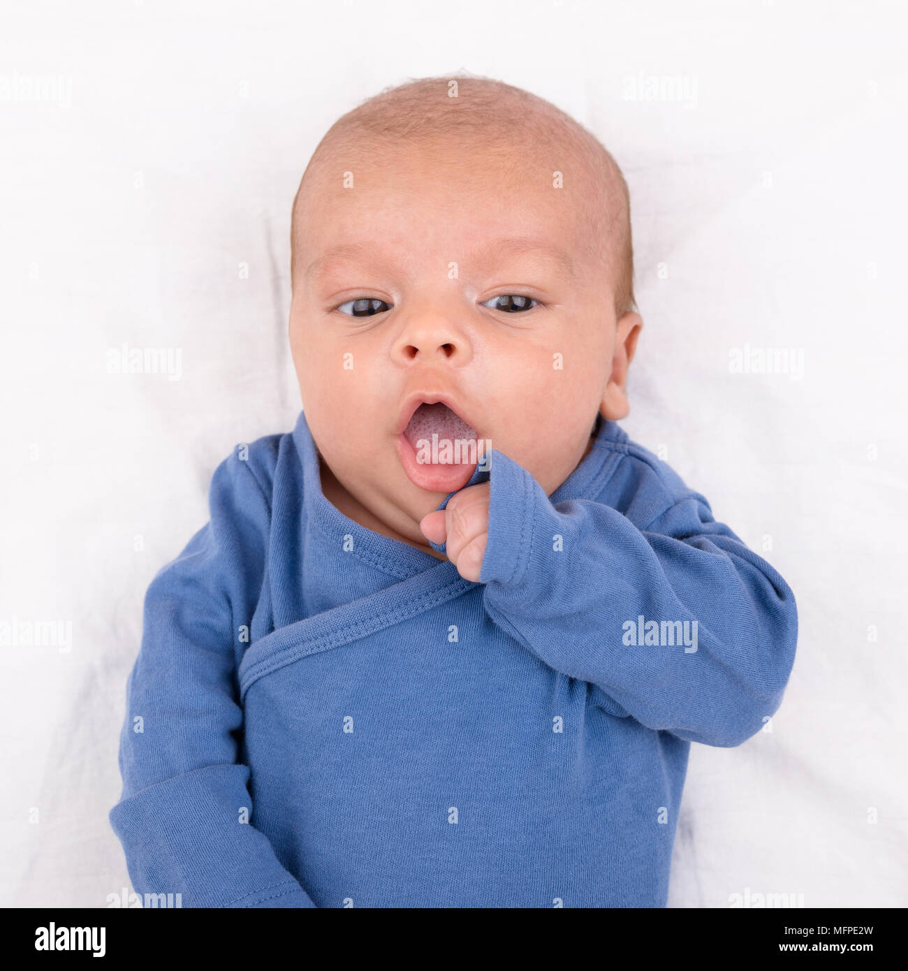 Cute eurasischen neugeborenes Baby Boy trägt ein blaues baby bodysuit auf weißem Blatt Stockfoto