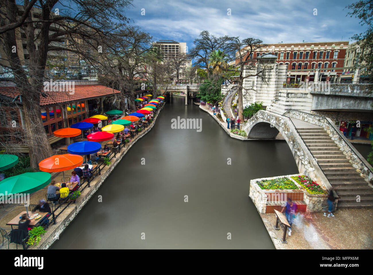 Teil der San Antonio Riverwalk mit Menschen zu Fuß über eine Brücke über den Fluss und die Gebäude und Restaurants in Spring, Texas, USA Stockfoto