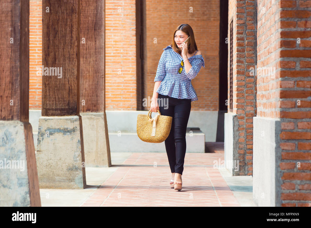 Glückliche junge asiatische Frau in Nizza legere und bequeme Kleidung leger Wandern an Ihrem lokalen Shopping Ort, während Sie telefonieren, gut für junge Stockfoto