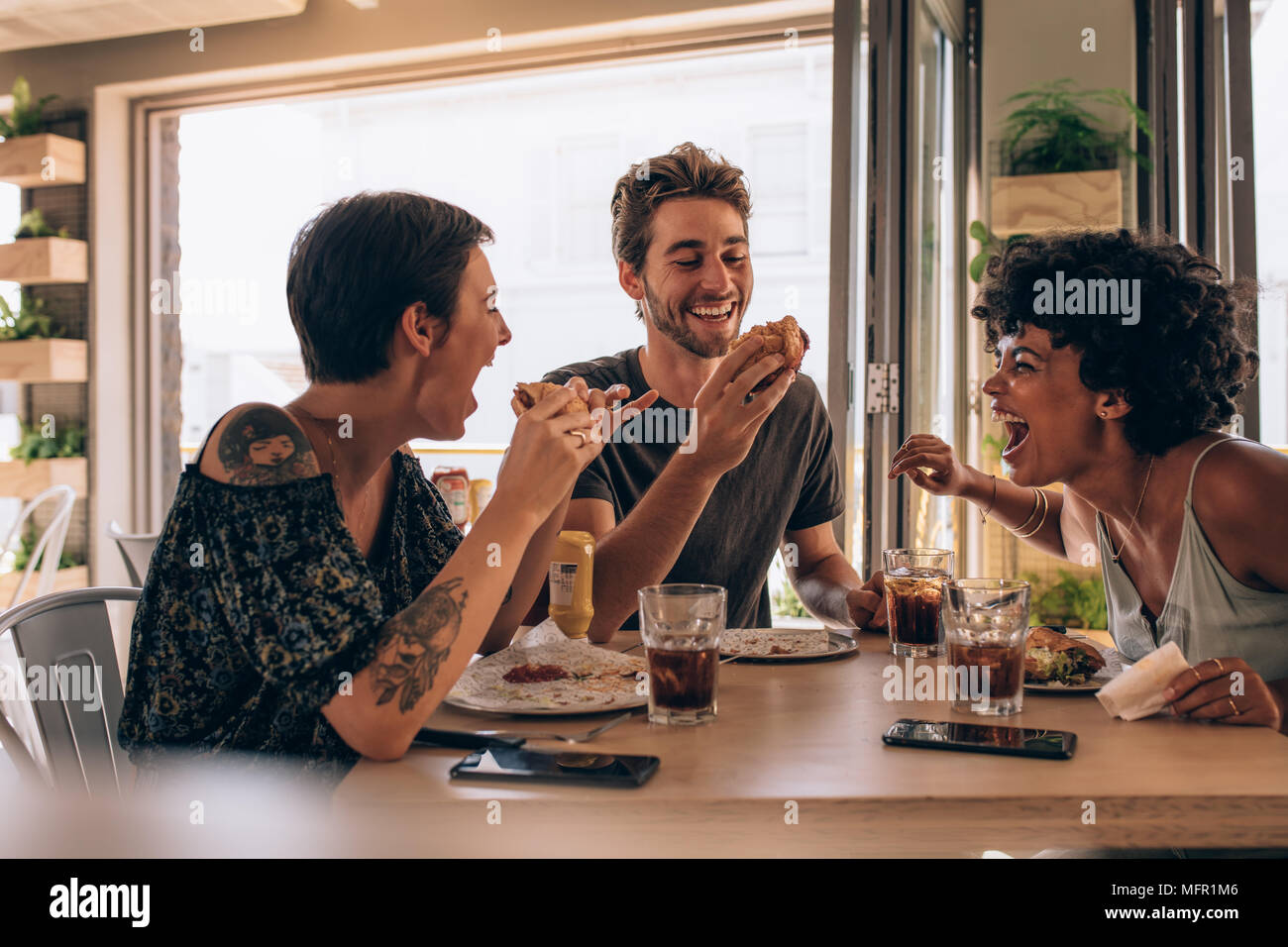 Gruppe von Freunden Burger mit Restaurant. Fröhlicher junger Menschen Burger essen und genießen in einem Fast Food Restaurant. Stockfoto