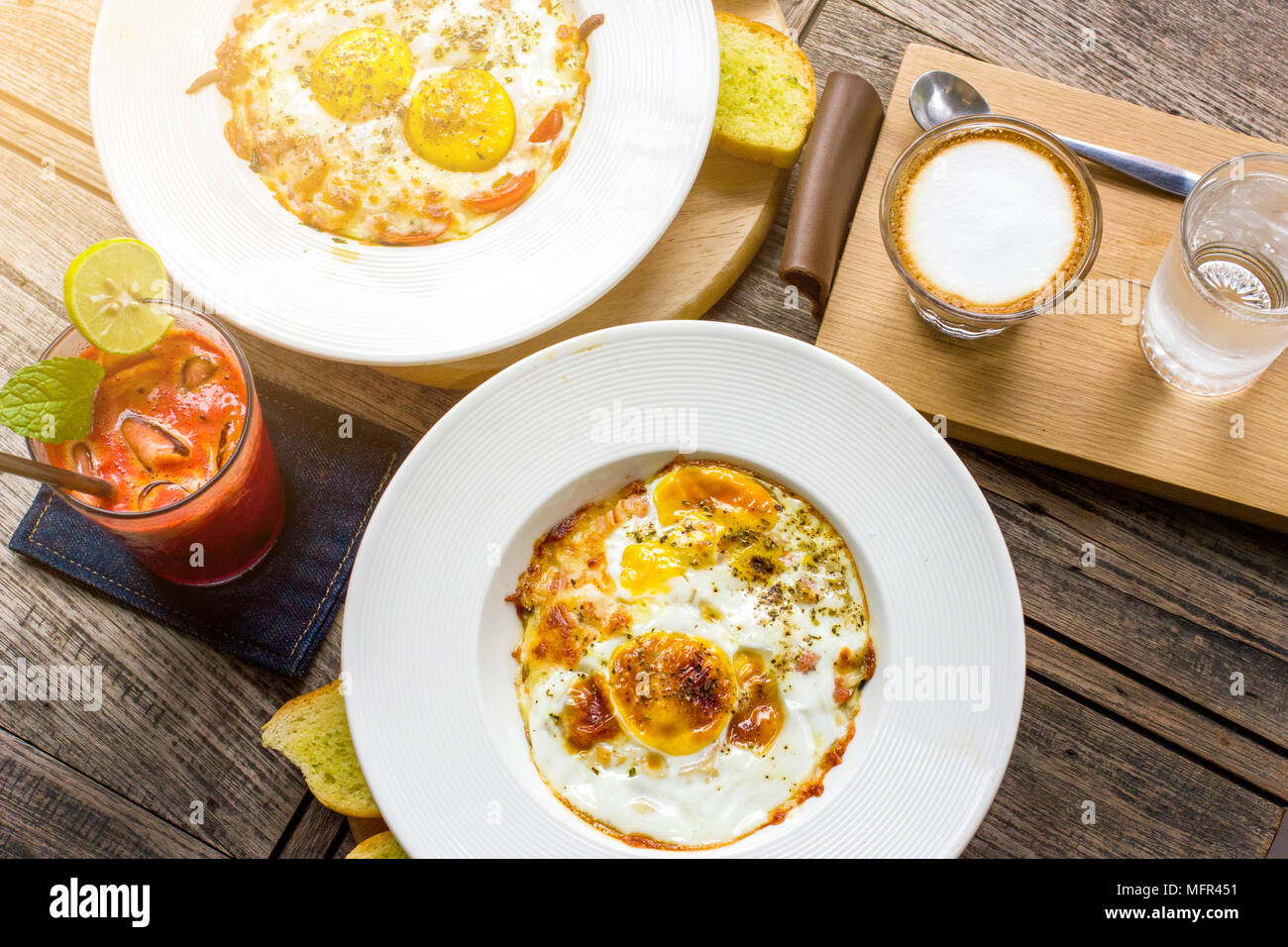 Spiegeleier serviert am Tisch mit Cappuccino und mix Fruchtsaft zum Frühstück Stockfoto