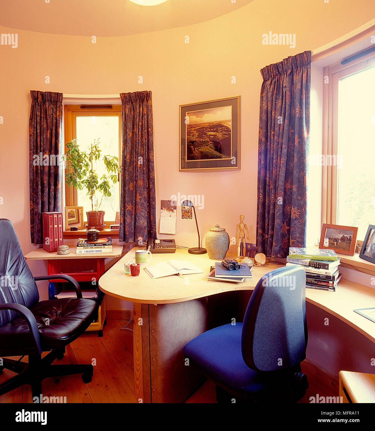 Bürobereich in Runde country house neutralen Wänden geformte Tisch Stühle gerahmtes Bild Ornamente Zimmerpflanze Topf windows Vorhänge Bodenplatte aus Holz Stockfoto