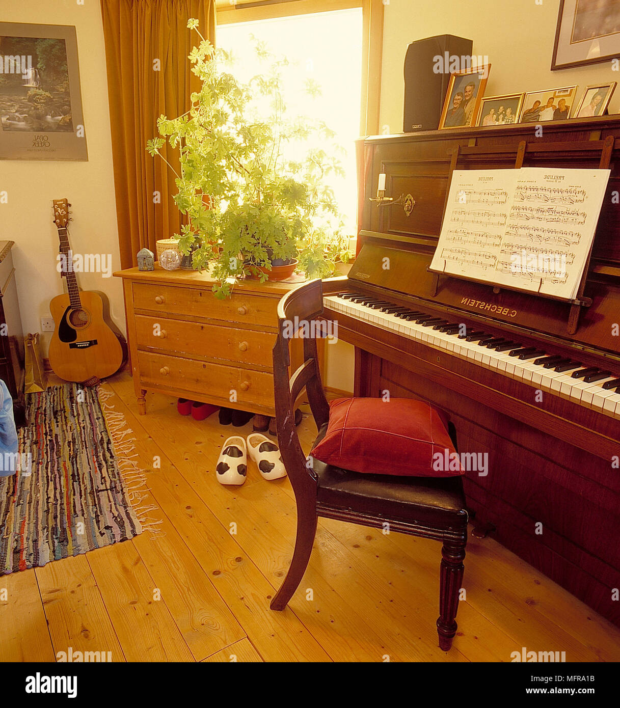 Klavier in Land Schlafzimmer von Round House neutrale Wände Sitzkissen Open Music buch Kommode Gitarre gerahmte Bilder Ornamente Zimmerpflanze öffnen Stockfoto