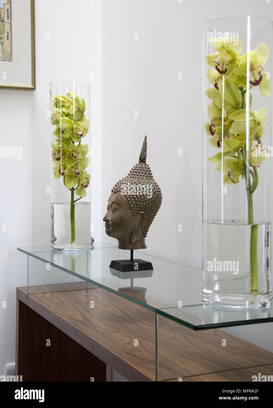 Paar Blumenarrangements in Glasvasen entweder Seite des Buddha Kopf  Abbildung auf Glas überstieg Beistelltisch Stockfotografie - Alamy