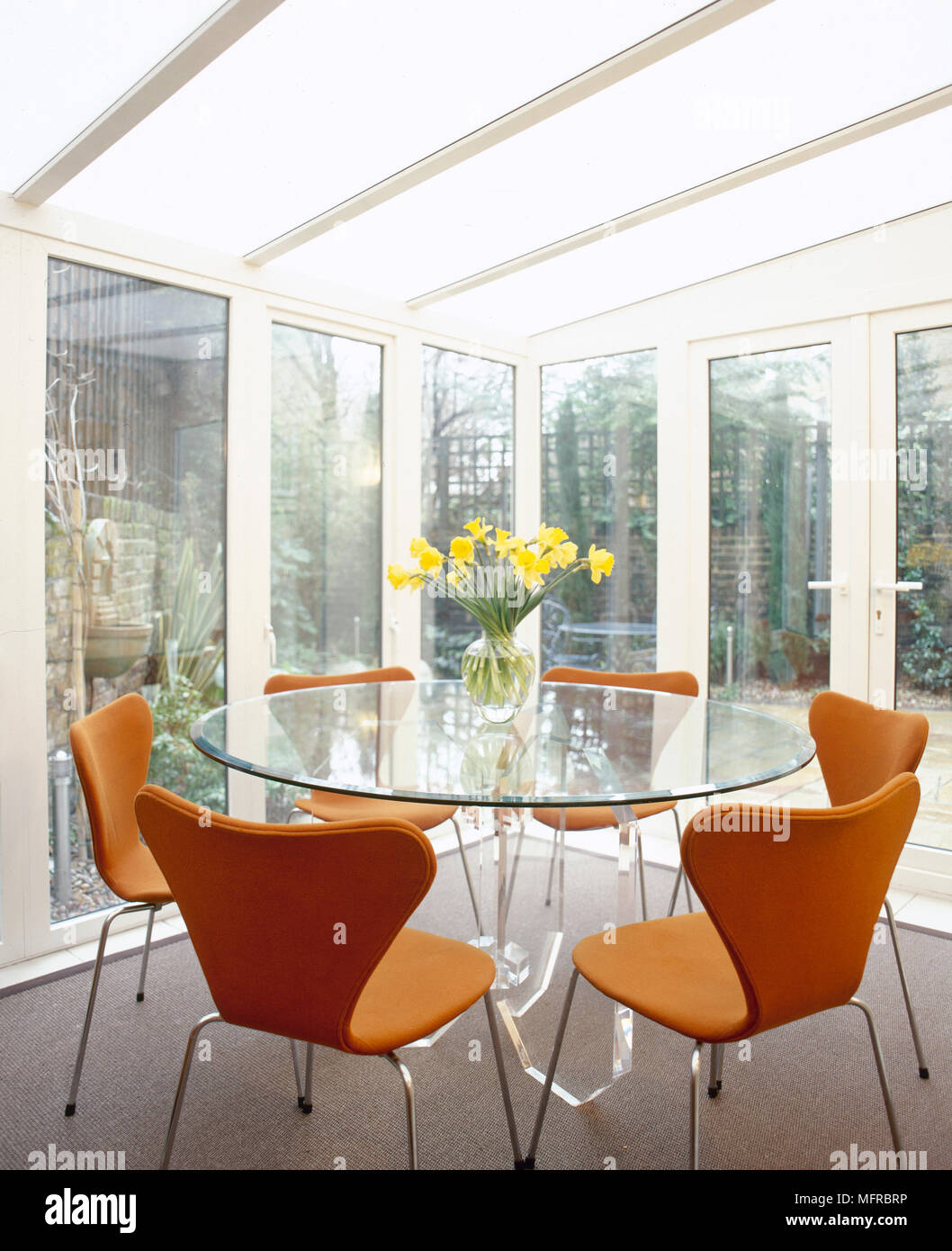 Modernen Wintergarten Essbereich Mit Glasernen Wanden Und Dach Runder Glastisch Und Butterfly Zuruck Stuhlen Stockfotografie Alamy