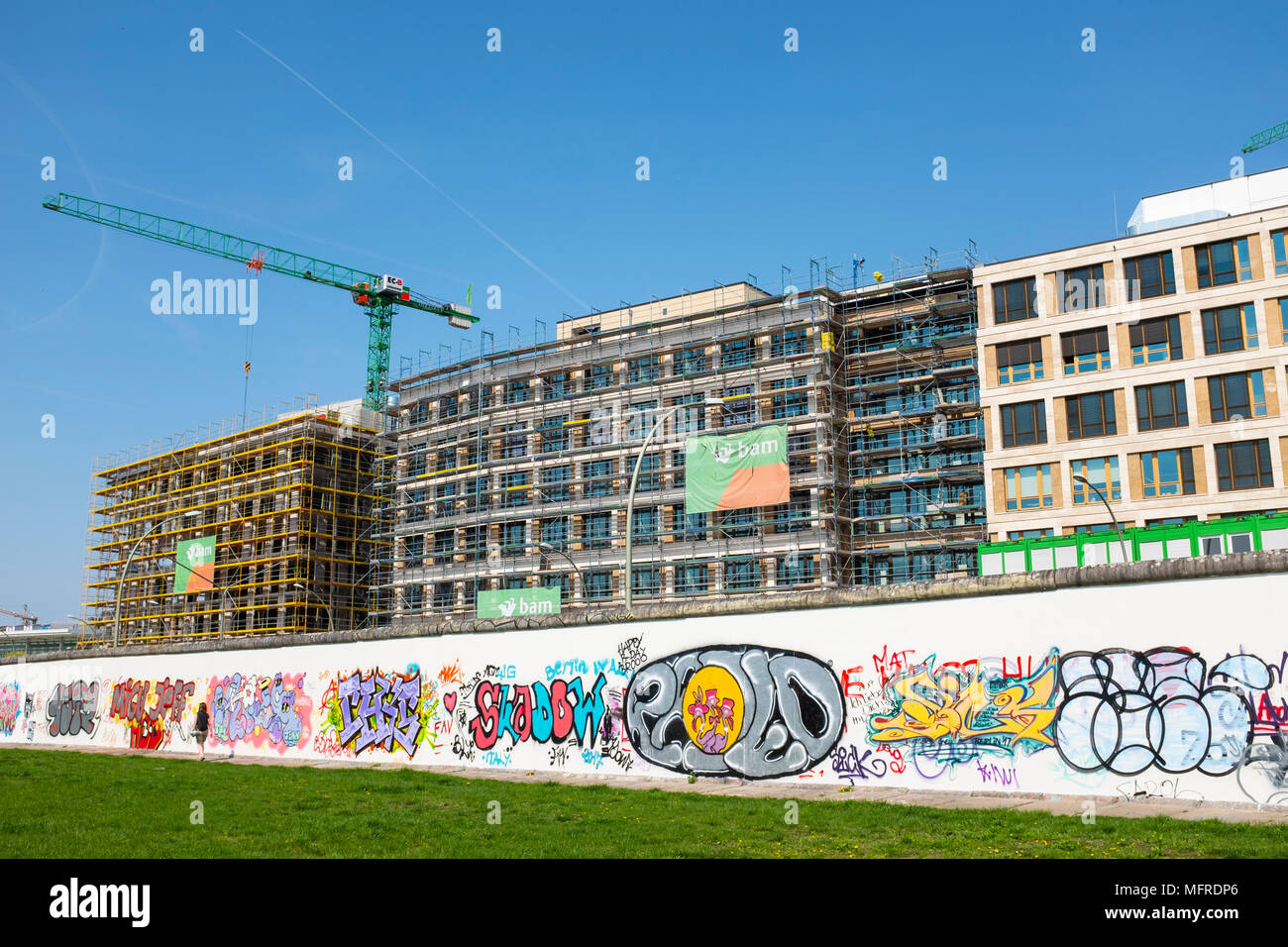 Blick auf den ursprünglichen Abschnitt der Berliner Mauer mit neuen Bürogebäude im Bau nach hinten an der East Side Gallery in Friedrichshain, Berlin, Deutschland. Stockfoto