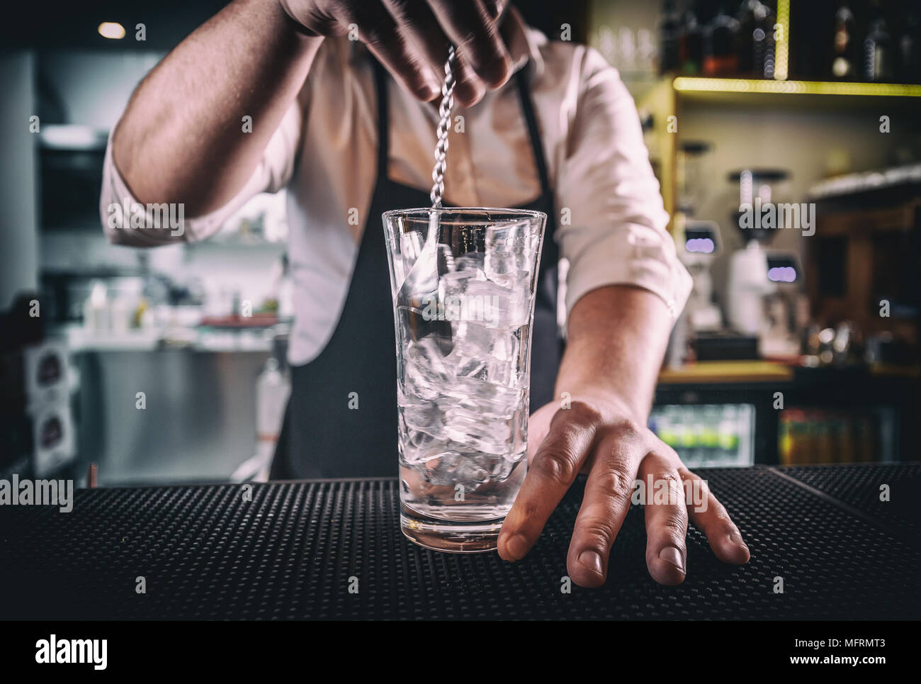 Professionelle Barkeeper bei der Arbeit in der Bar Mixing Eis mit Wodka im Glas für Getränk Stockfoto