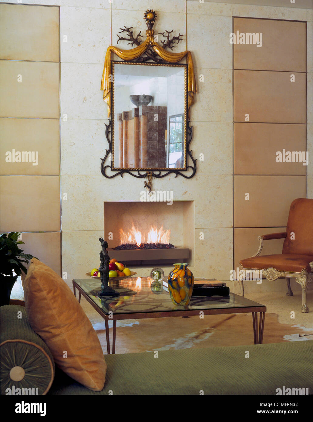Ein Detail einer modernen Wohnzimmer mit einfachen Kamin mit Feuer angezündet Zeitraum Sessel Couchtisch aus Glas Stockfoto