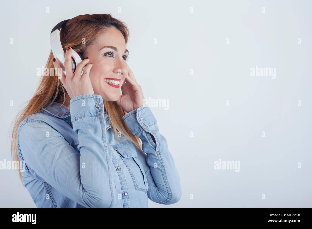 Glückliche junge Frau mit Kopfhörer auf weißem Hintergrund Stockfoto