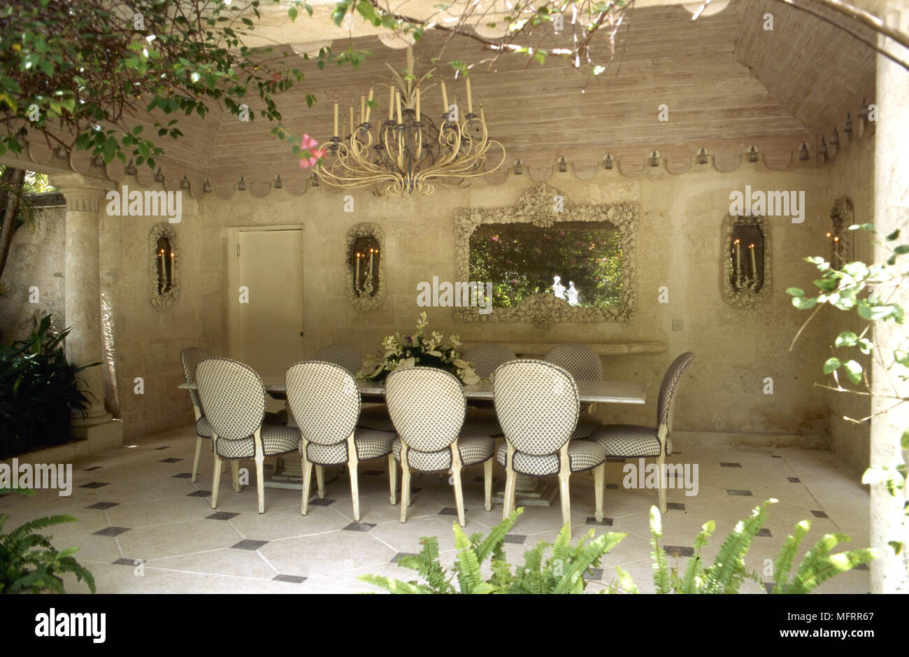 Überdachte Terrasse Essbereich mit steinernen Wänden, gefliestem Fußboden,  Esstisch mit gepolsterten Stühlen und eine Kerze Kronleuchter  Stockfotografie - Alamy