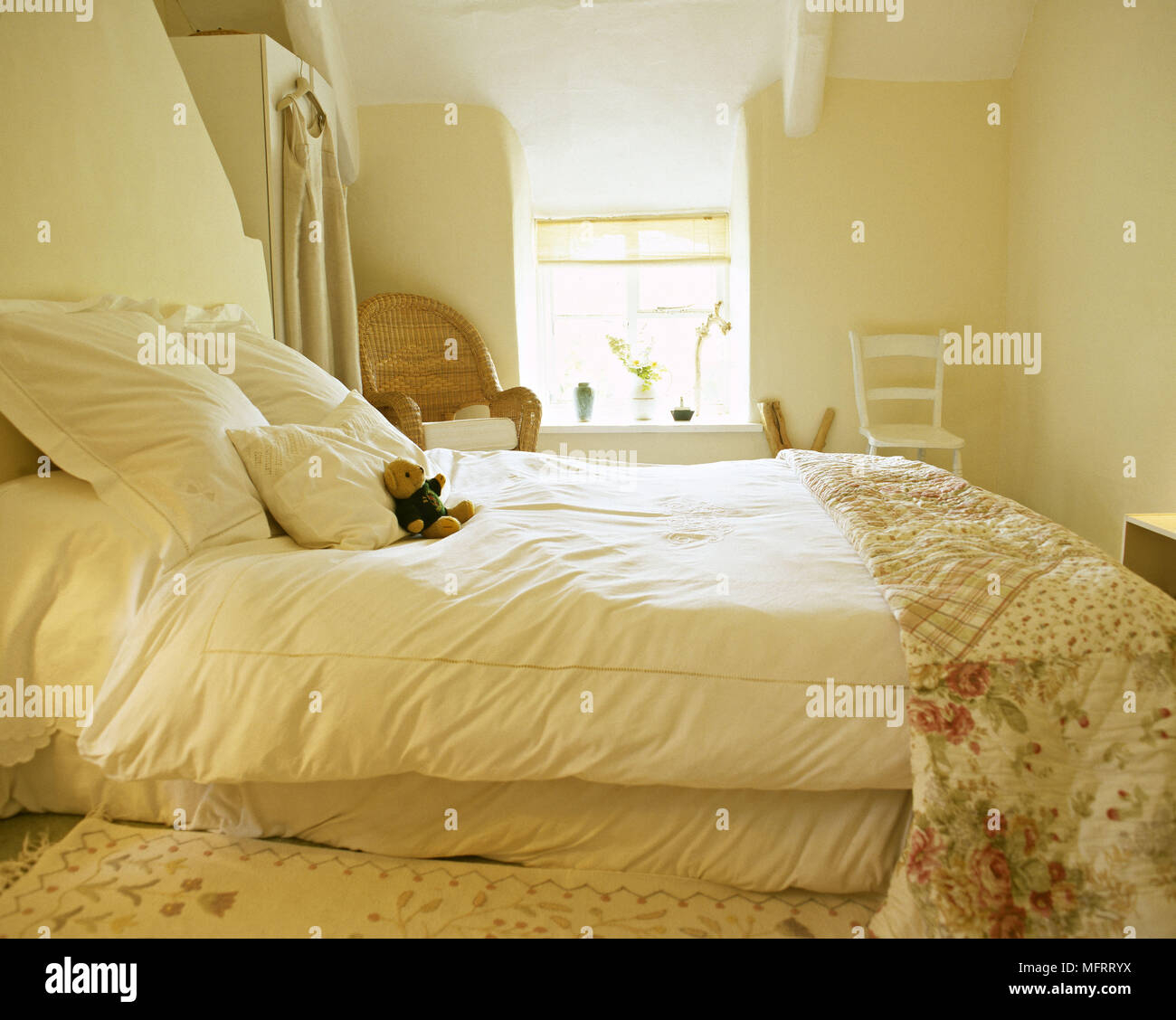 Land gelbe Schlafzimmer mit floralen Bettdecke und einem sonnigen Fenster. Stockfoto