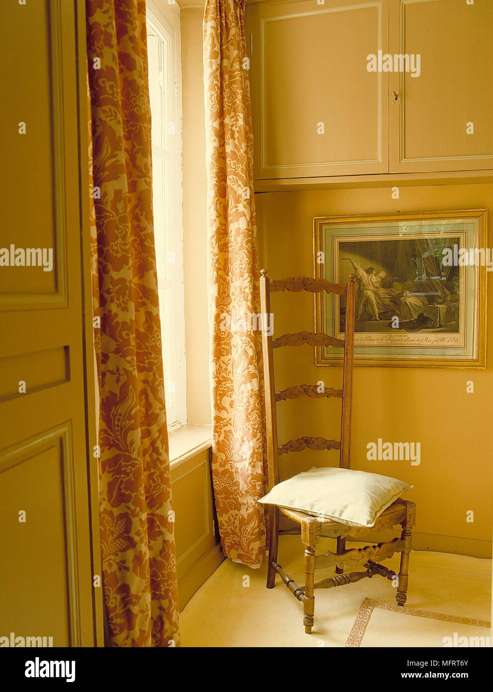 Hohe gesichert Stuhl in der Ecke traditionelle Schlafzimmer gelben Wänden Kissen Einbauschränke gerahmtes Bild Interieur Schlafzimmer Fenster Detail Behandlungen drap Stockfoto