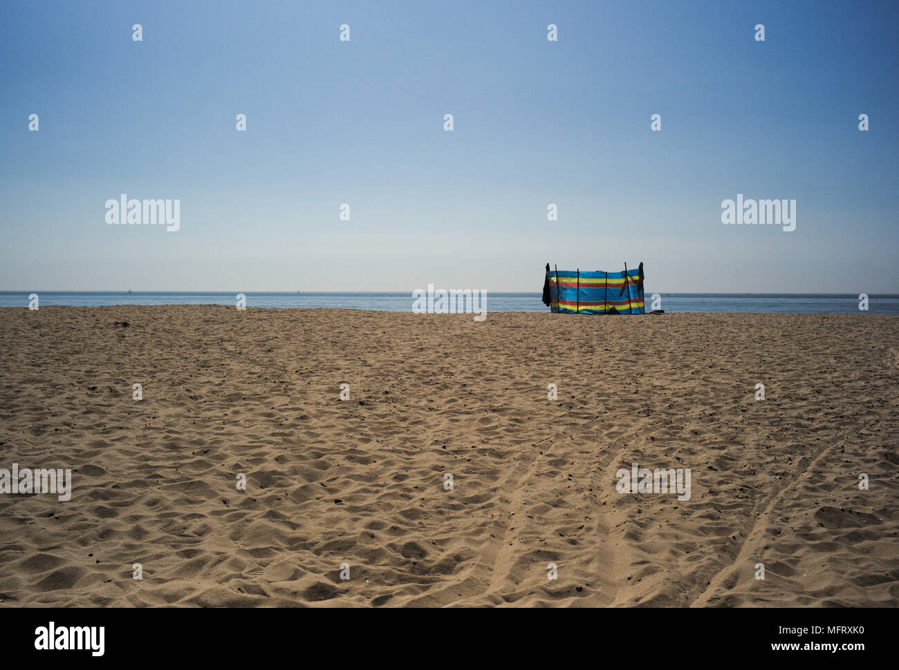 Eine leere Sandstrand Szene an einem sonnigen Tag mit blauem Himmel und Horizont mit einem farbigen wind Bruch mit kopieren. Der Strand ist Bournemouth in England. Stockfoto