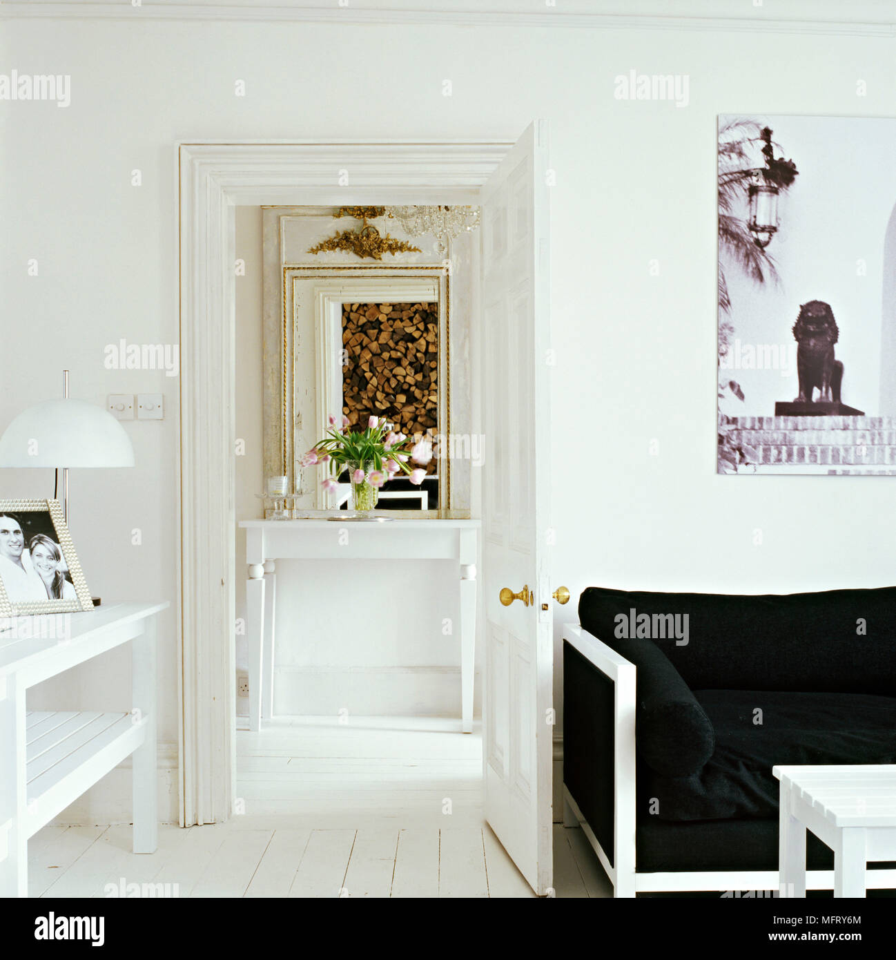 Ein Detail einer modernen weißen Wohnzimmer weiß lackiert Holz Sofa mit schwarzem Polster offene Tür zum Flur Stockfoto