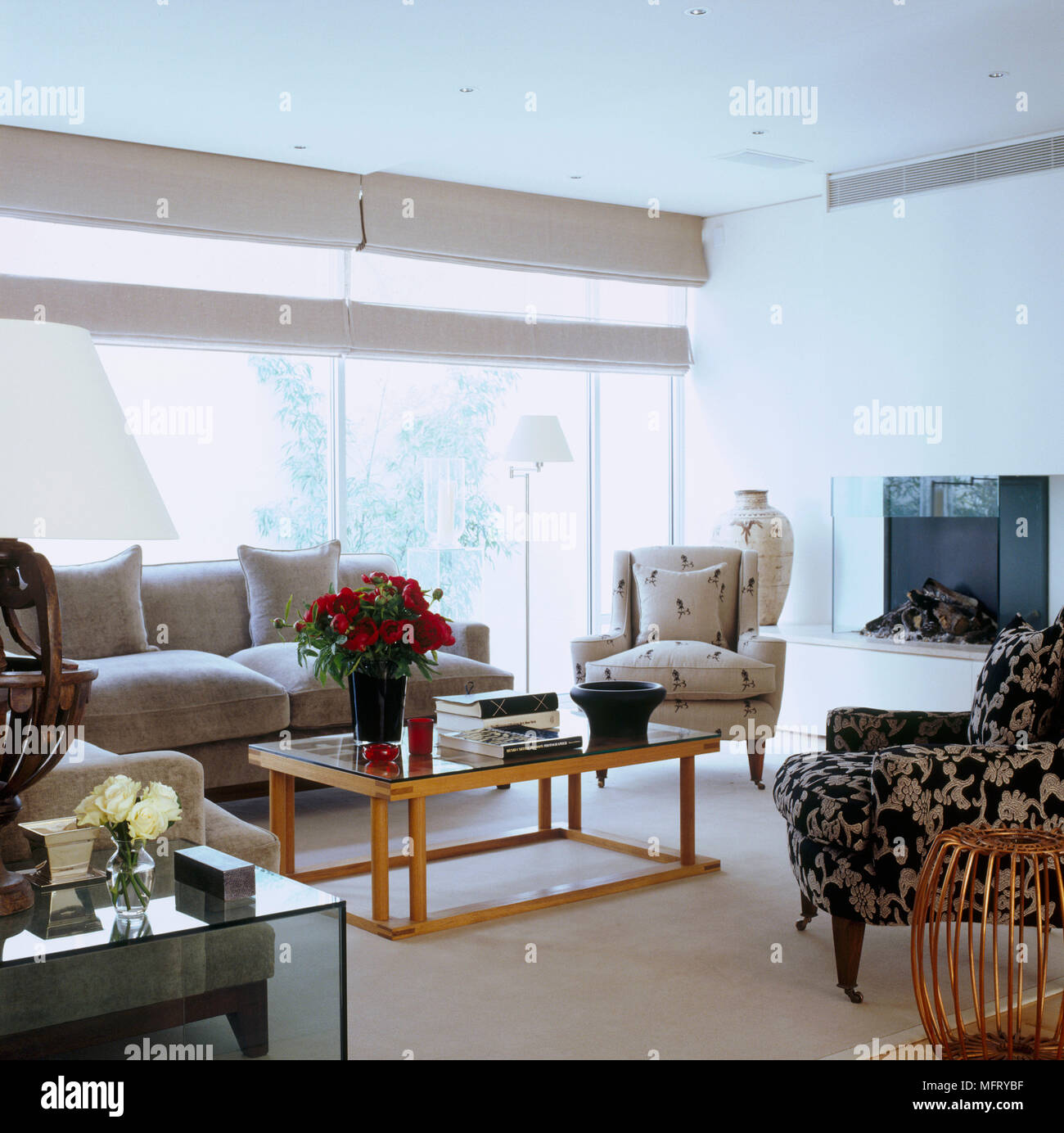 Eine moderne neutral Wohnzimmer mit Kamin traditionelle gepolsterte Sessel Couchtisch Raffrollos Stockfoto