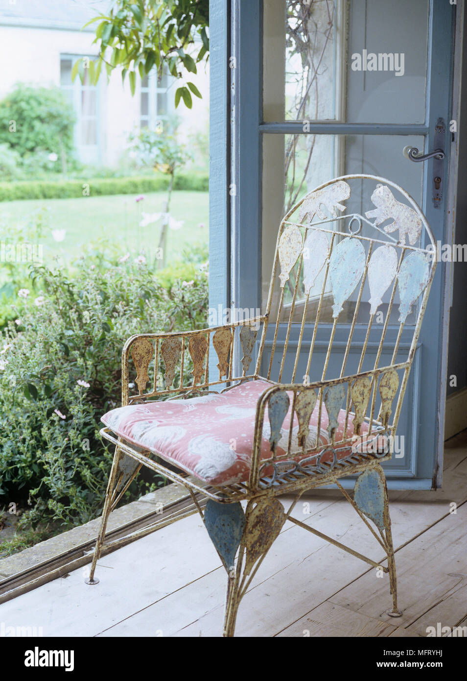 Detail der traditionellen Landhausstil Stuhl durch eine offene Tür nach Außen Stockfoto