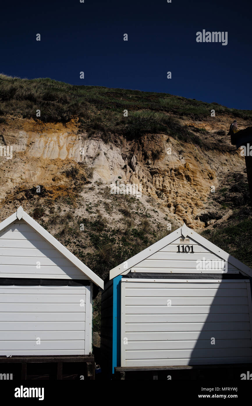 Freiliegende Felsen Geologie an der Strand von Bournemouth Dorset aus dem Eozän alter hier oben die vielen Badekabinen am Strand gezeigt. Stockfoto