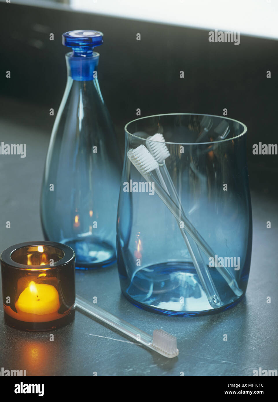Blaue Gläser mit Zahnbürsten und orange Glas Kerzenhalter mit geschmolzenen  Kerzenlicht Stockfotografie - Alamy