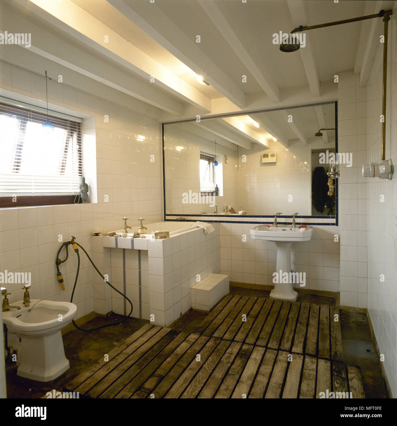 Rustikal, Land Bad mit gefliesten Wänden, offener Dusche, Balkendecke, Gelattete Holzböden und großem Spiegel. Stockfoto