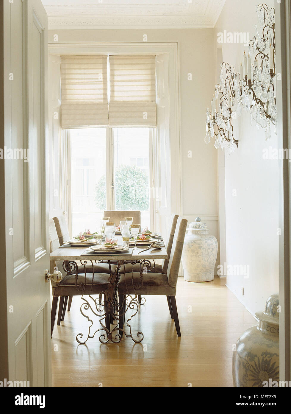 Blick durch die offene Tür zu einem modernen neutralen Esstisch und Stühle Holz, Glas Wandleuchten Stockfoto