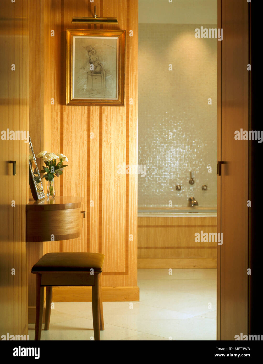 Ein Blick durch die offene Tür in einer modernen Bad mit Holztäfelung an der Wand montierte Frisiertisch Hocker Badewanne Stockfoto