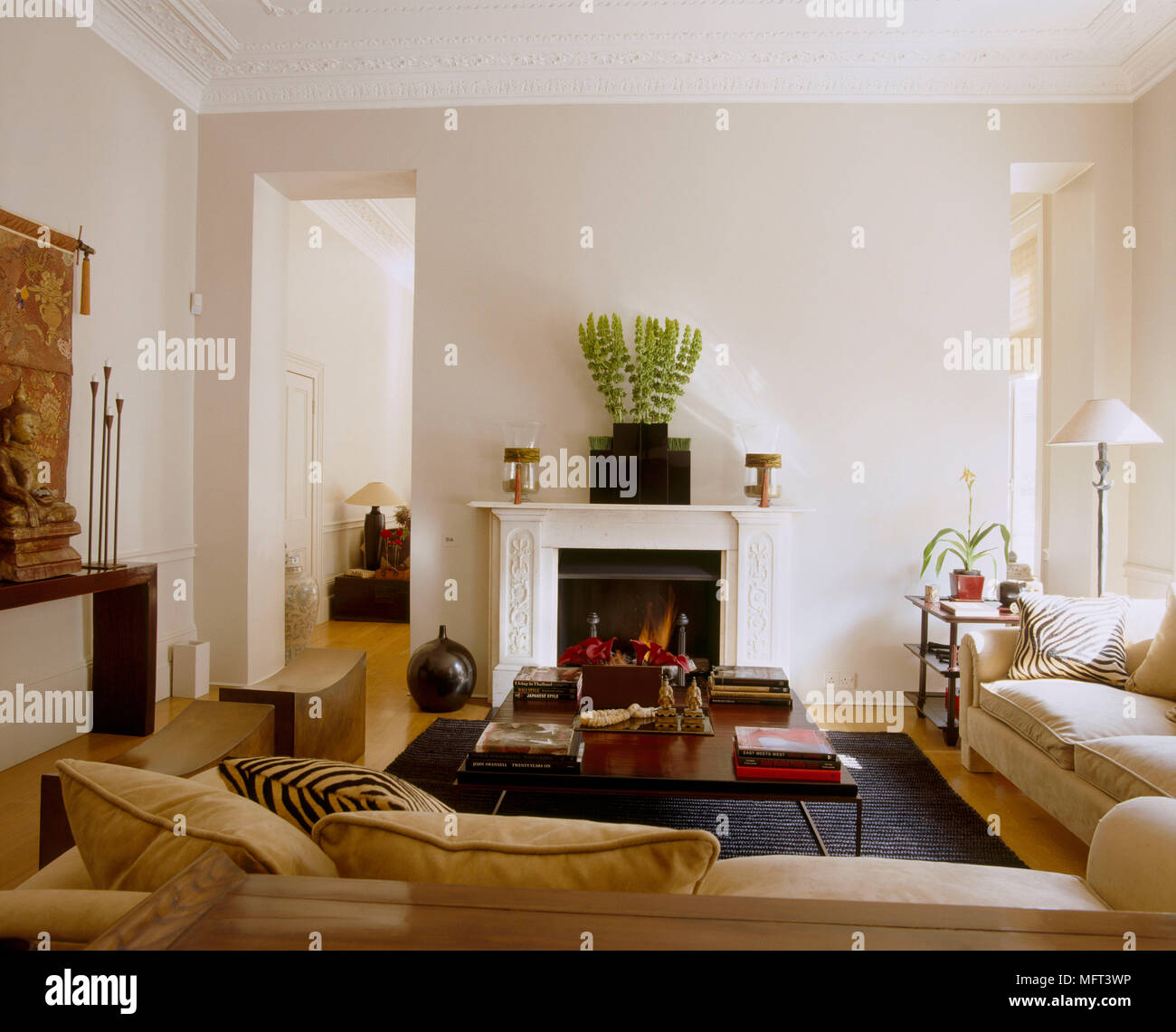 Eine Traditionelle, in neutralen Wohnzimmer Kamin mit Feuer angezündet gepolstertes Sofa Holz Couchtisch Stockfoto
