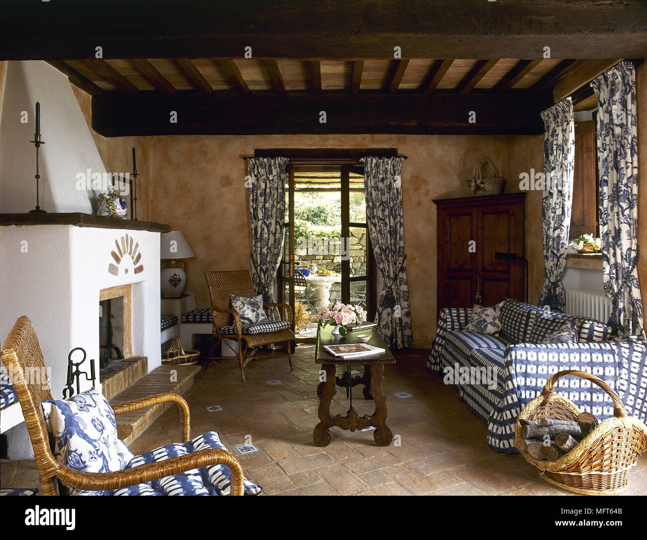 Rustikale terracotta Wohnzimmer mit Holzbalkendecke und Kamin, Muster  Vorhänge am Fenster Stockfotografie - Alamy