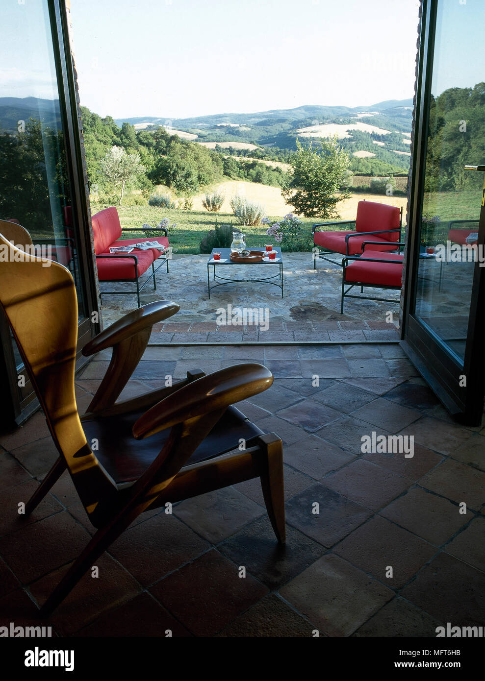 Fliesen Wintergarten Mit Einem Holzernen Sessel Und Offnen Turen Zu Einer Terrasse Mit Aussicht Stockfotografie Alamy