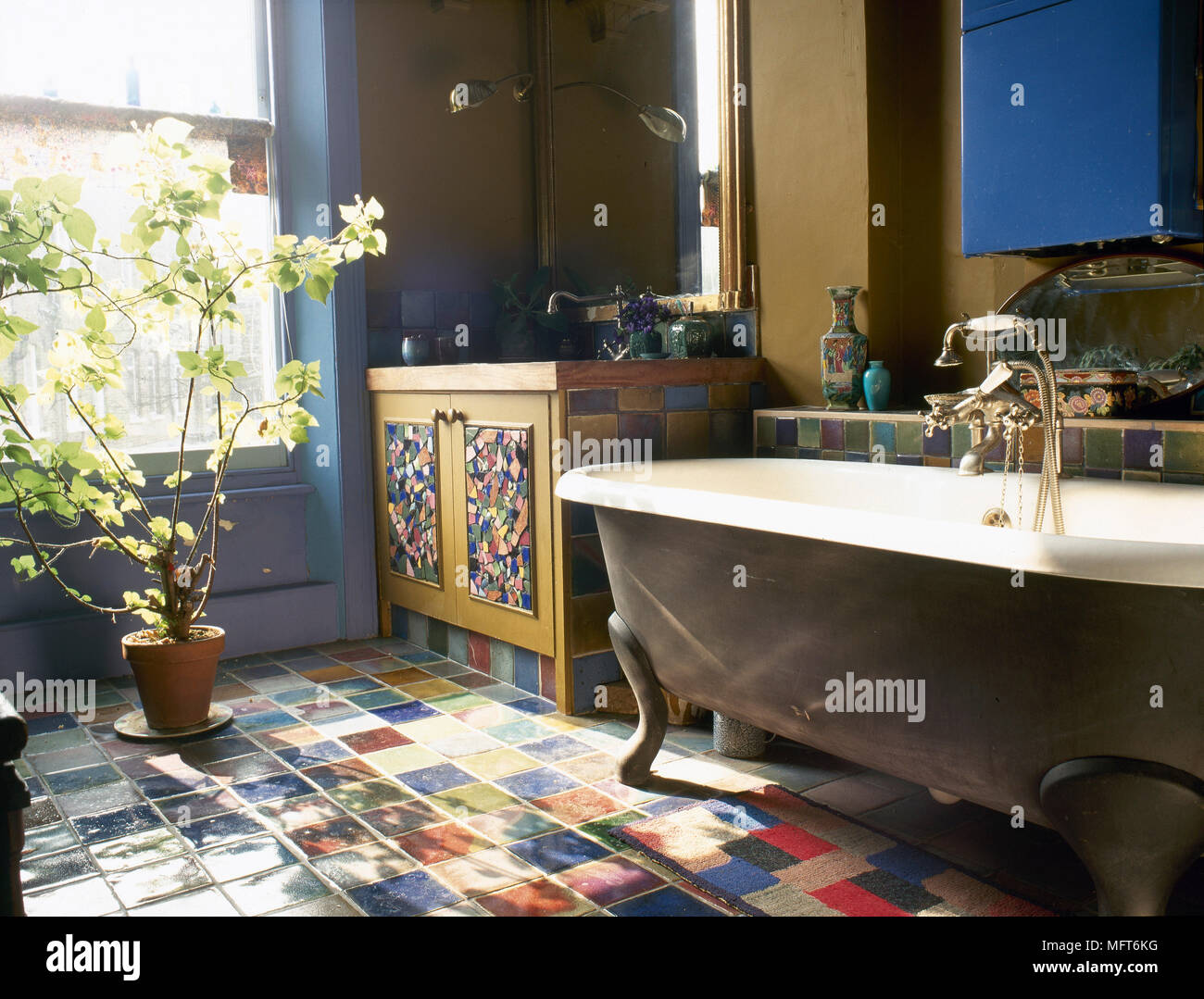 Land Bad Detail mit dekorativen Mosaikfußboden und Waschbecken, freistehende freistehende Badewanne und eine Topfpflanze am Fenster. Stockfoto