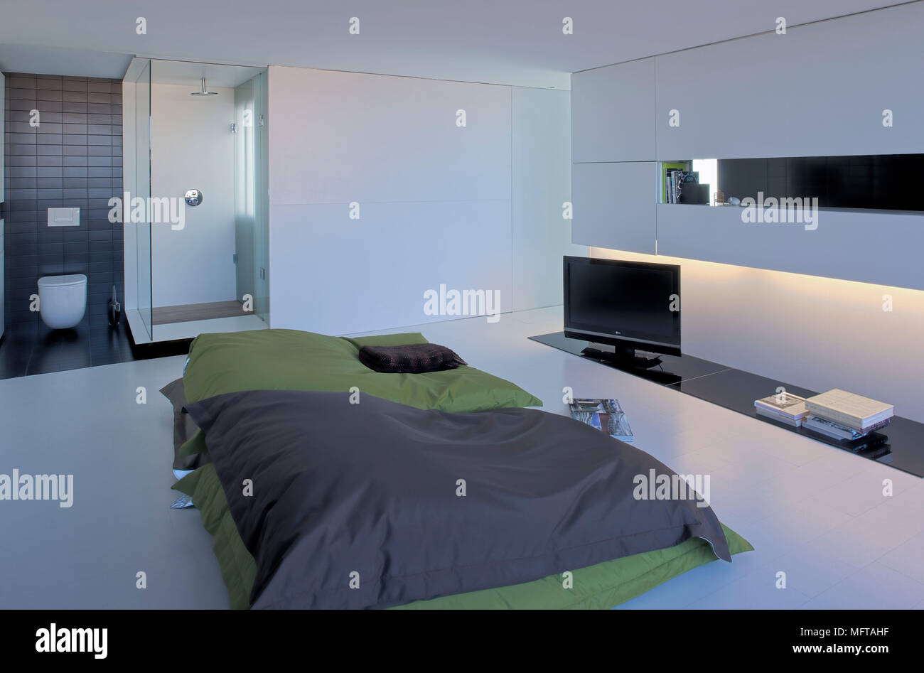 Stock Kissen vor Breitbildfernseher in modernes Schlafzimmer mit privatem Bad Stockfoto