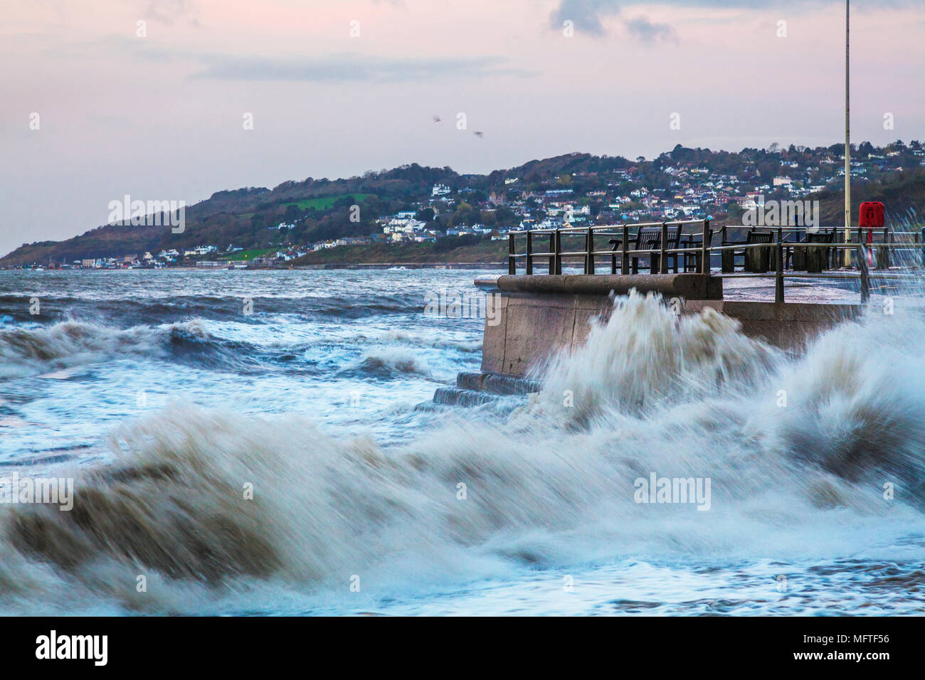 Wellen gegen die Quay bei Charmouth, Dorset bei Sonnenaufgang brechen. Stockfoto