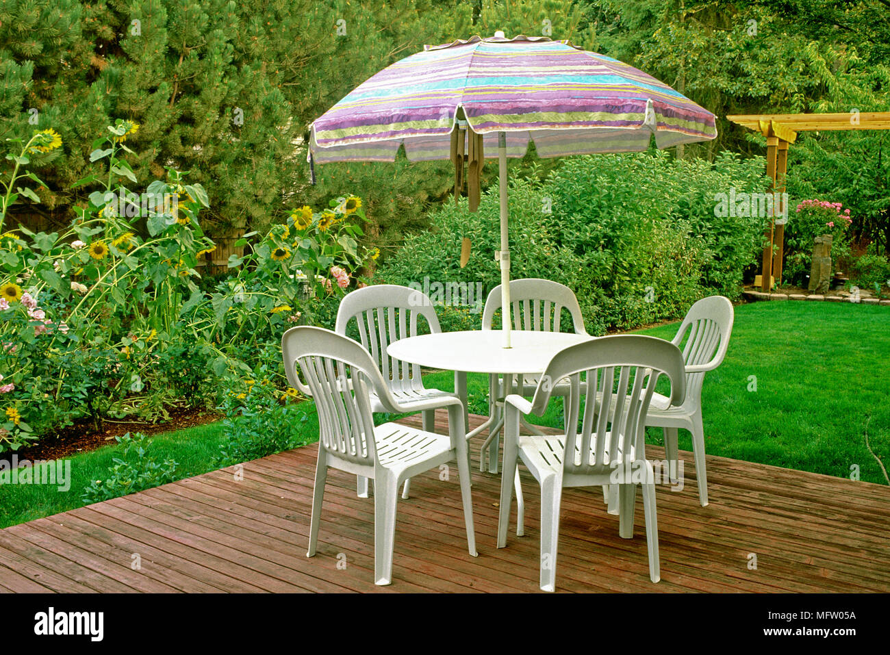 Kunststoff Tische und Stühle mit Sonnenschirm auf, überdachte Terrasse mit  Blick auf Garten Stockfotografie - Alamy