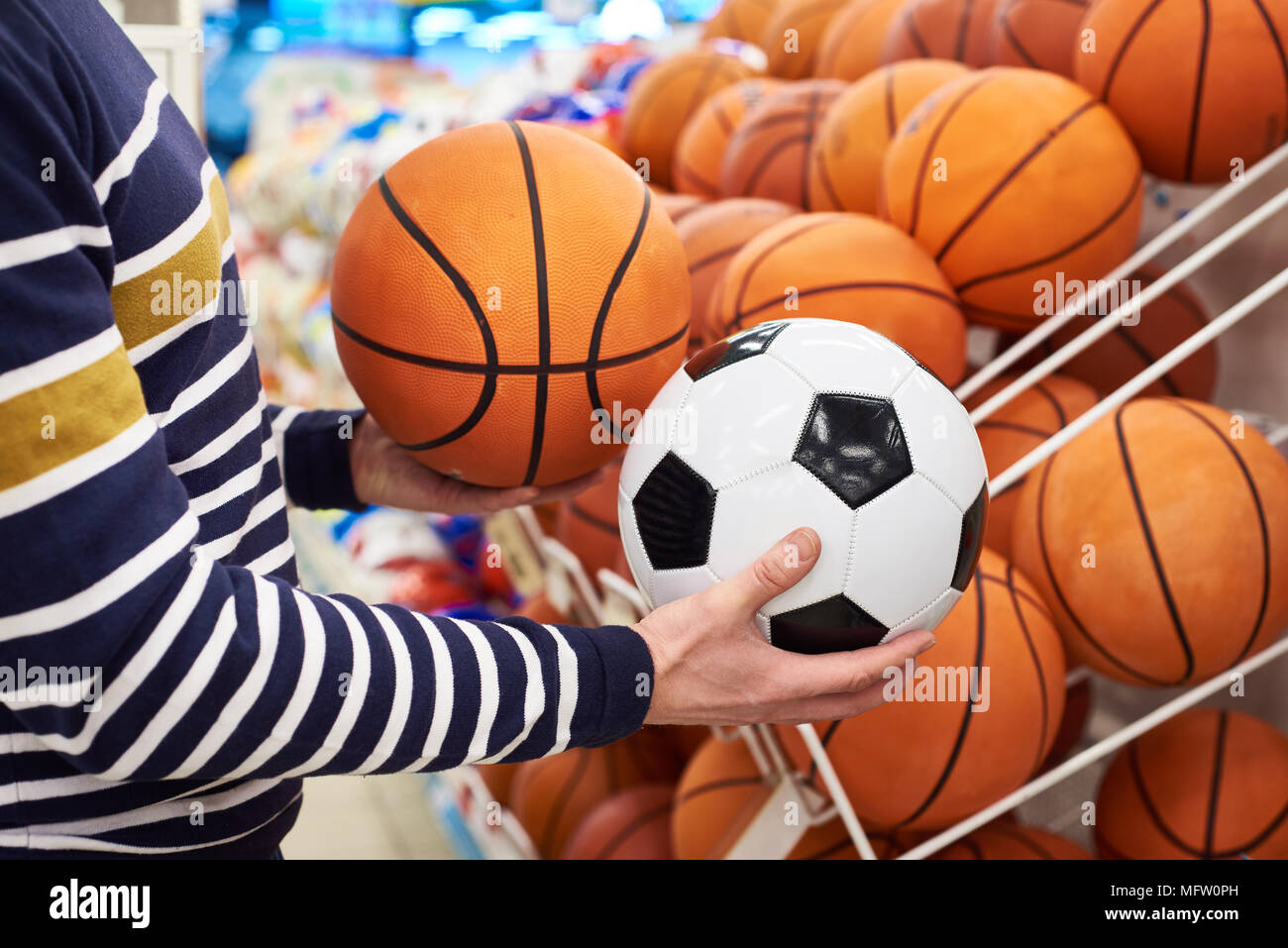 Buyer's Hände mit Fußball und Basketball in der Sport Shop Stockfoto