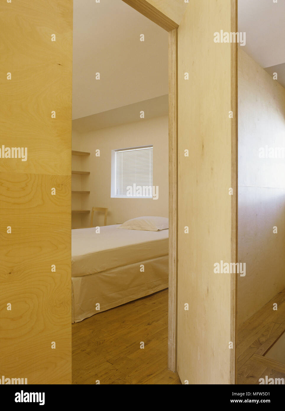 Blick durch die offene Tür zum Doppelbett im minimalistischen Schlafzimmer Stockfoto