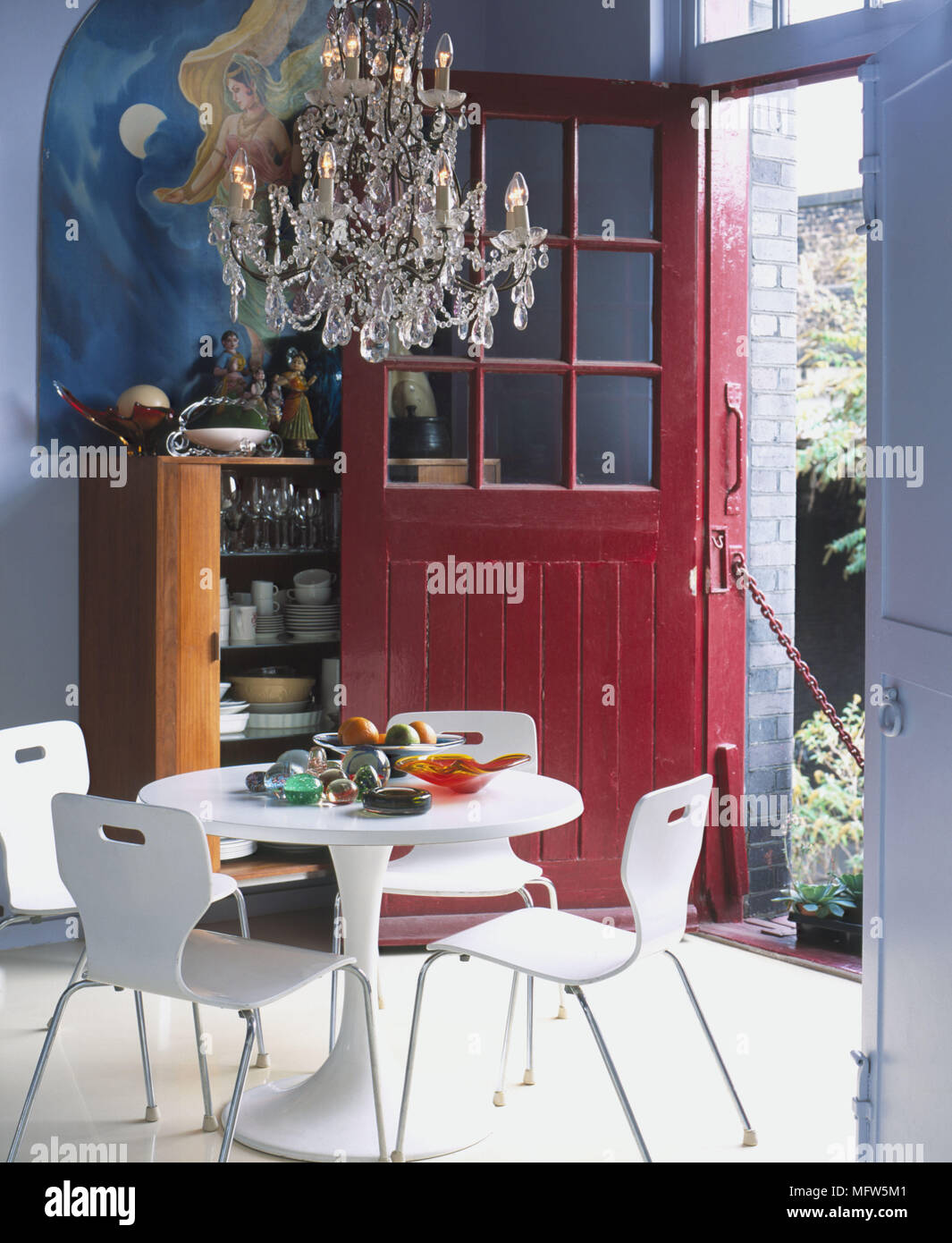 Einen modernen Speisesaal Kunststoff weiß Tisch und Stühle rot lackiert Kronleuchter aus der offenen Tür Schaltschrank Stockfoto