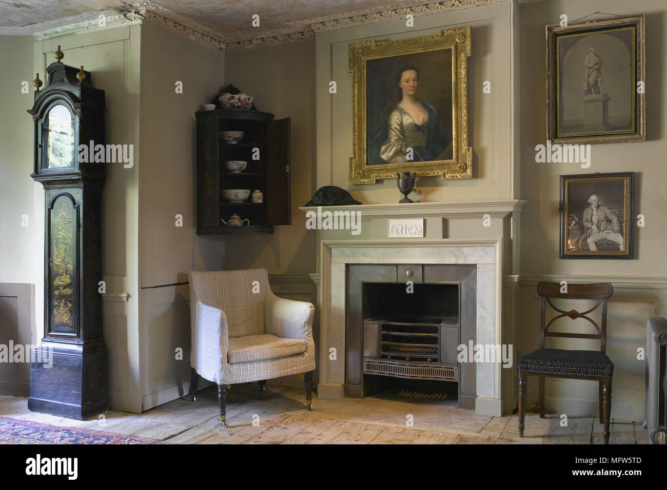 Ein traditionelles Wohnzimmer Kamin Standuhr abgestreift Dielen gepolstertem Sessel Stockfoto