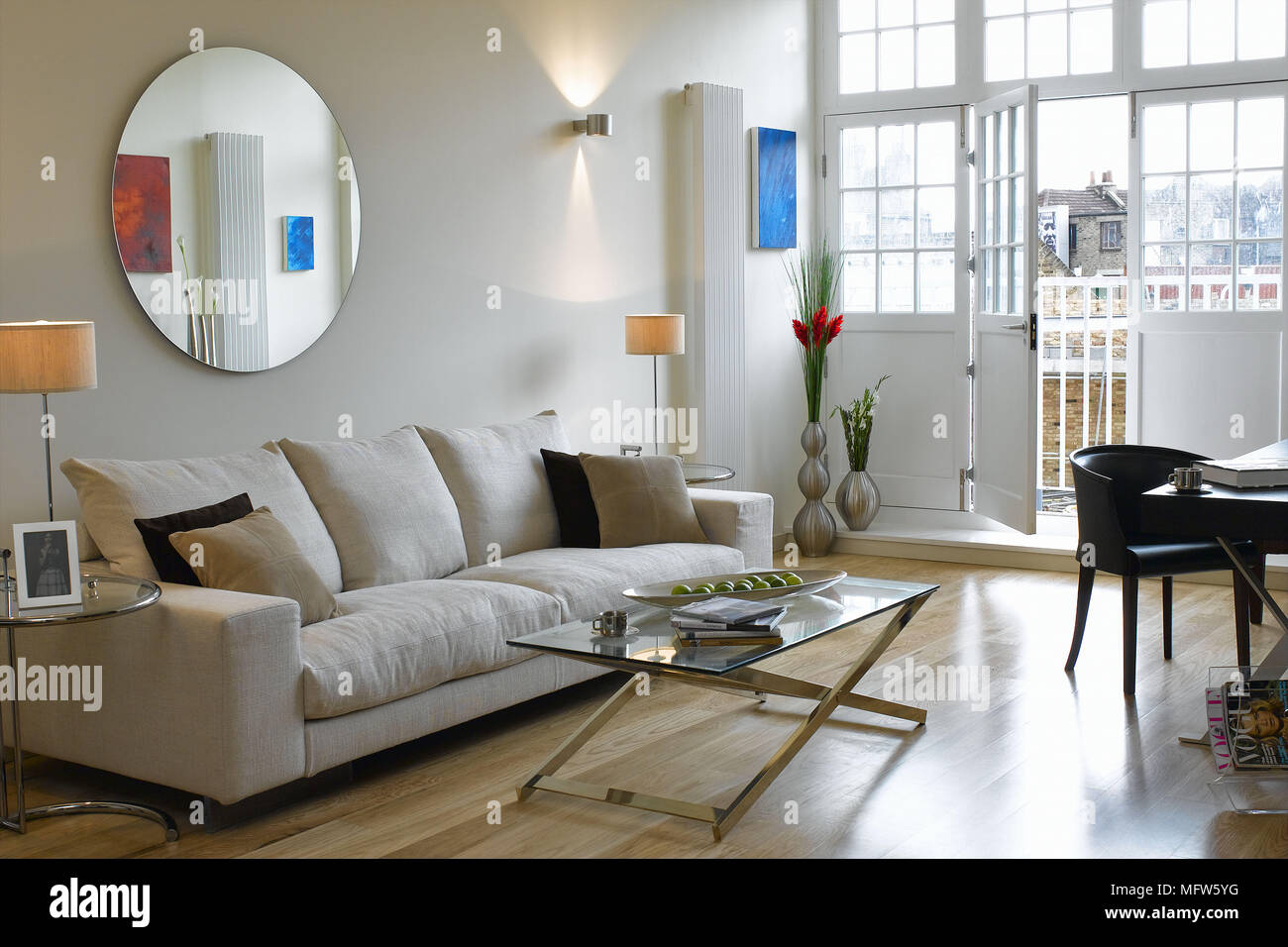Runder Spiegel über ein Sofa in ein Wohnzimmer mit einer offenen Terrasse. Stockfoto