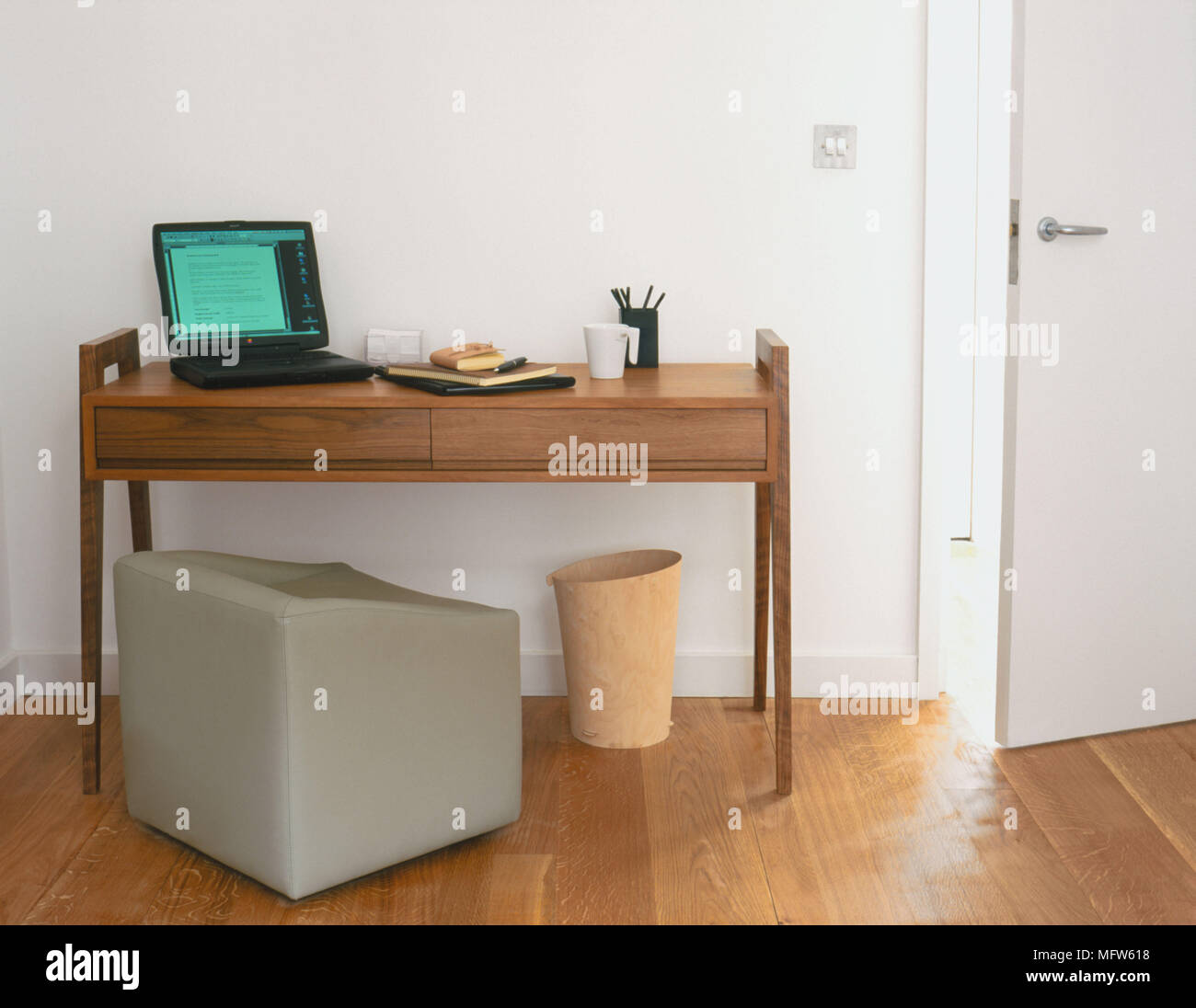 Details von einem Laptop auf einer einfachen, zeitgenössischen Holzmöbeln, Schreibtisch mit einem quadratischen Sitz vor. Stockfoto