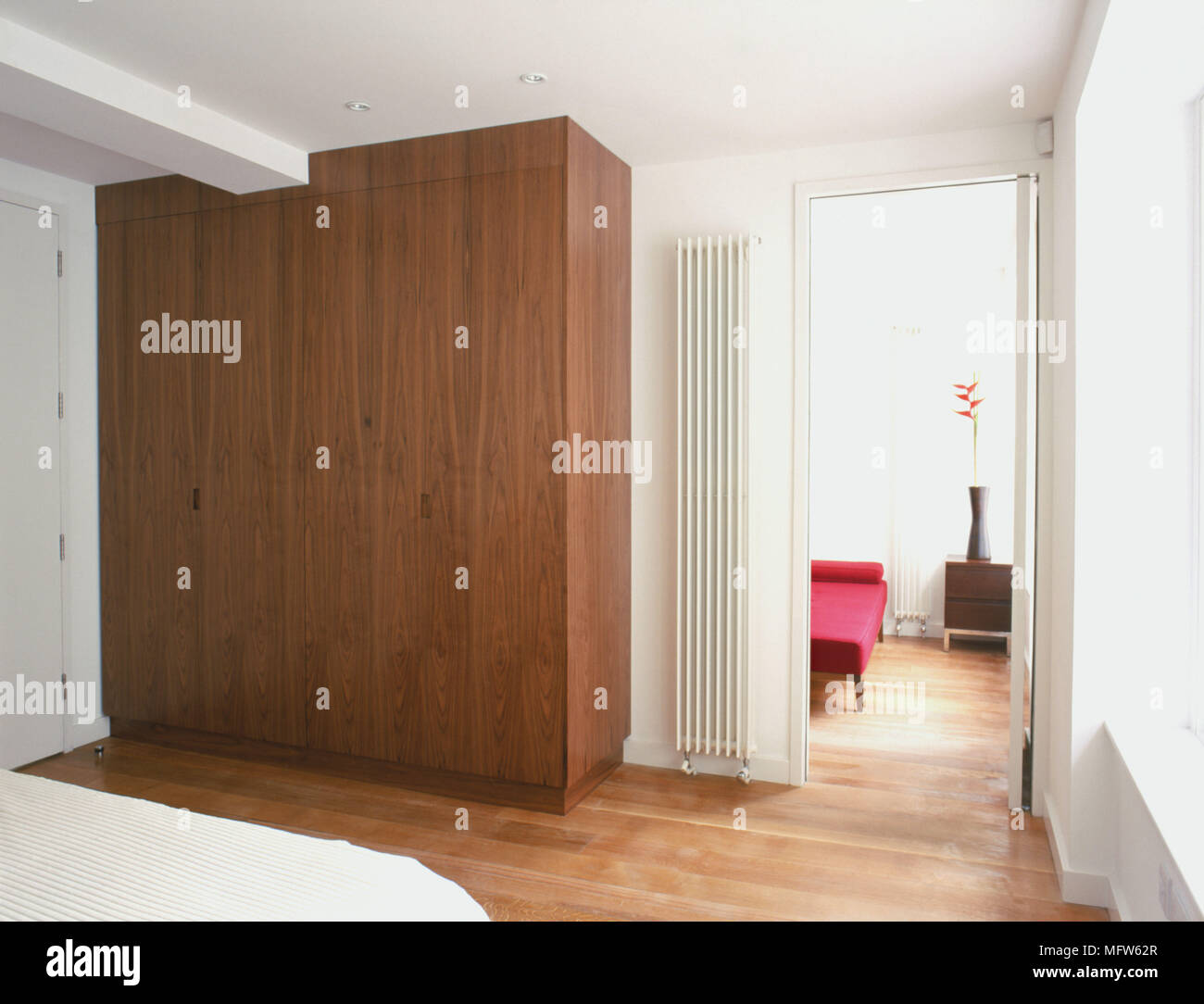 Details eines modernen, minimalistischen Schlafzimmer mit großem Kleiderschrank aus Holz neben einer vertikalen Kühler und eine Tür. Stockfoto