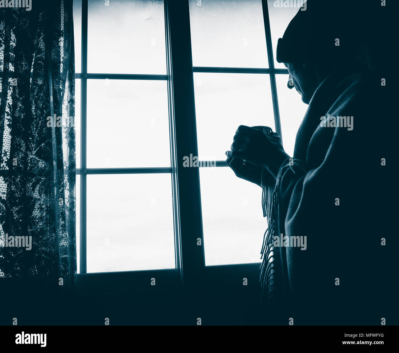 Reifer mann Holding cup Blick aus Fenster: Einsamkeit, psychische Gesundheit, die allein leben,... Konzept Bild Stockfoto