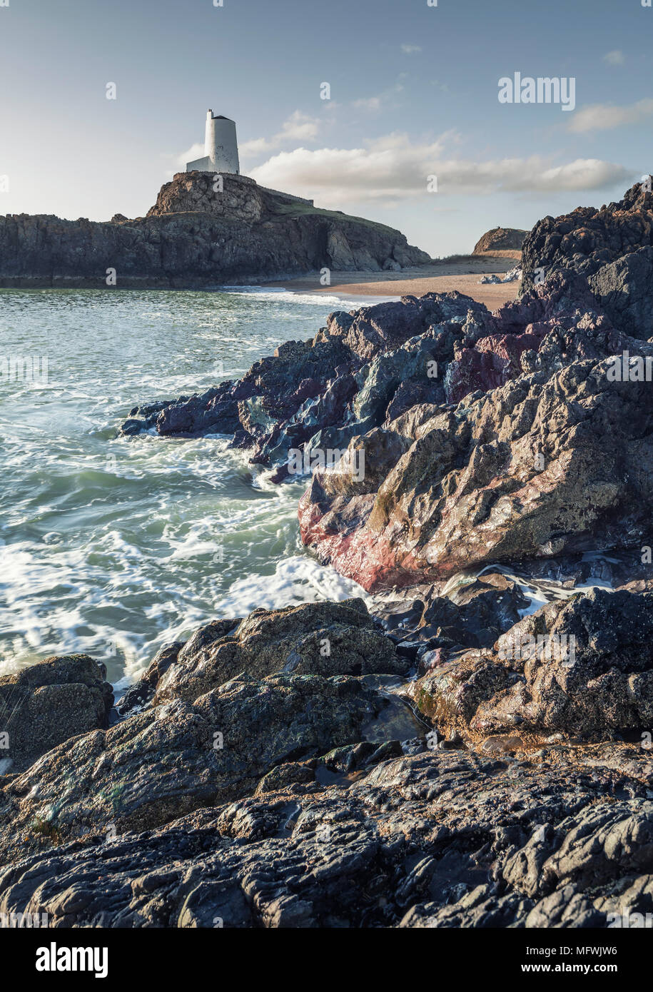 Felsigen Ufer mit alten lighhouse auf Felsen im Hintergrund. Ynys LLanddwyn im Nordwesten Anglessey, Wales, Großbritannien Stockfoto