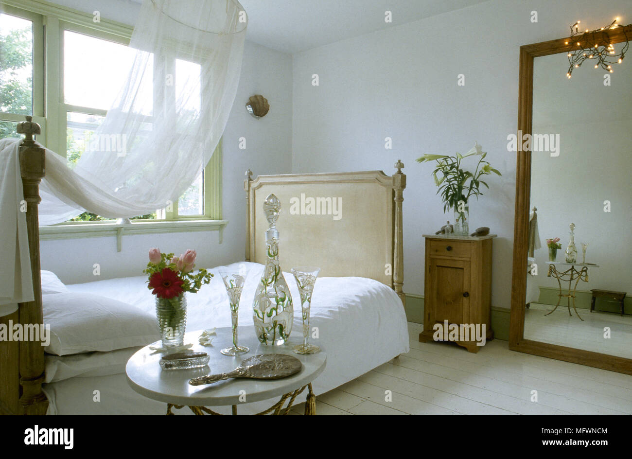 Romantisches Schlafzimmer mit Baldachin über ein Doppelbett, einen großen  Spiegel, Nachttisch und einem sonnigen Fenster Stockfotografie - Alamy
