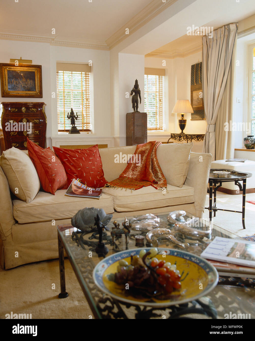Die gepolsterten Sofas mit roten Kissen vor Glas Couchtisch Stockfoto