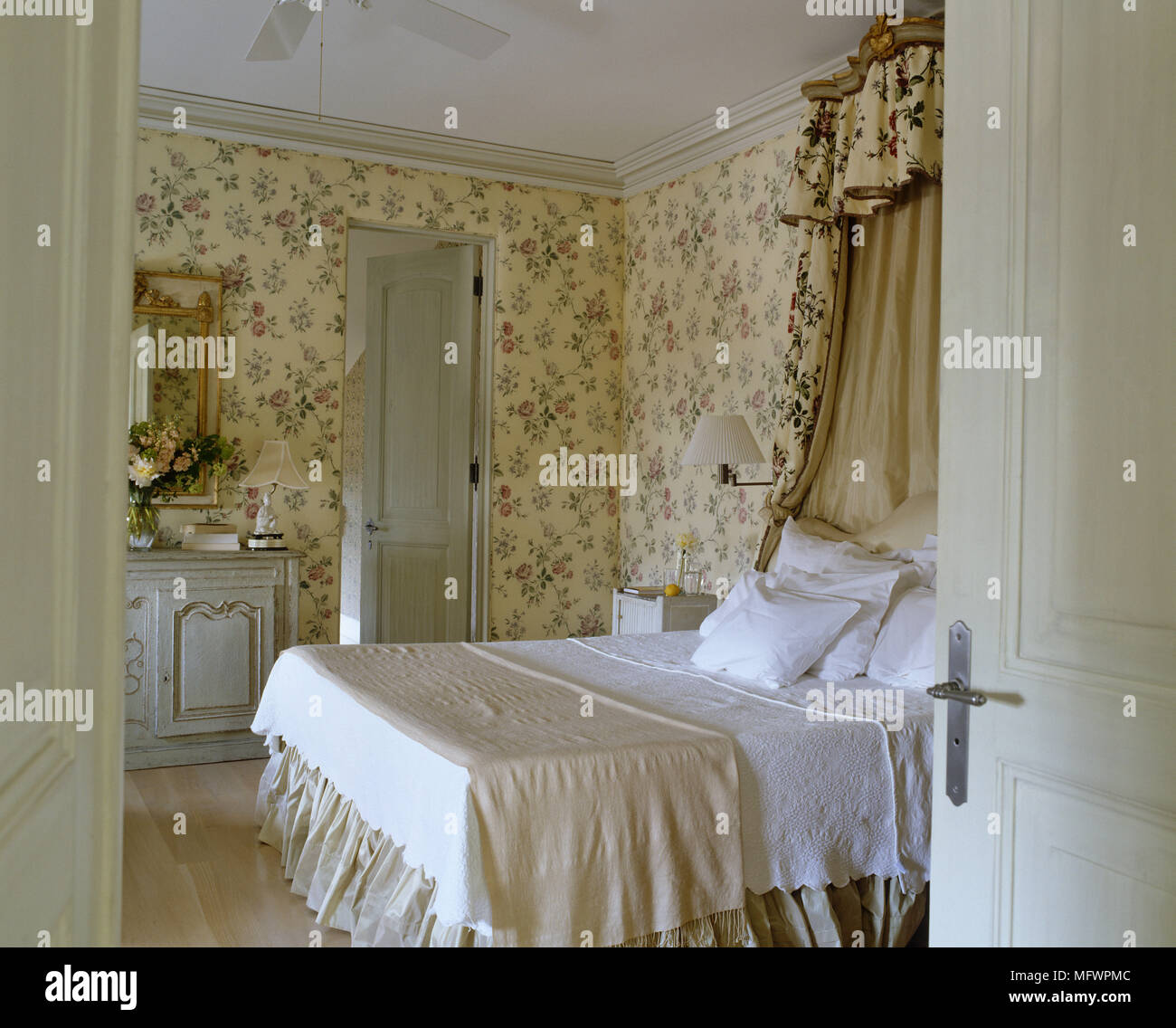 Blick durch die offene Tür zu Doppelbett im Schlafzimmer mit Blumenmuster wallpaper Stockfoto