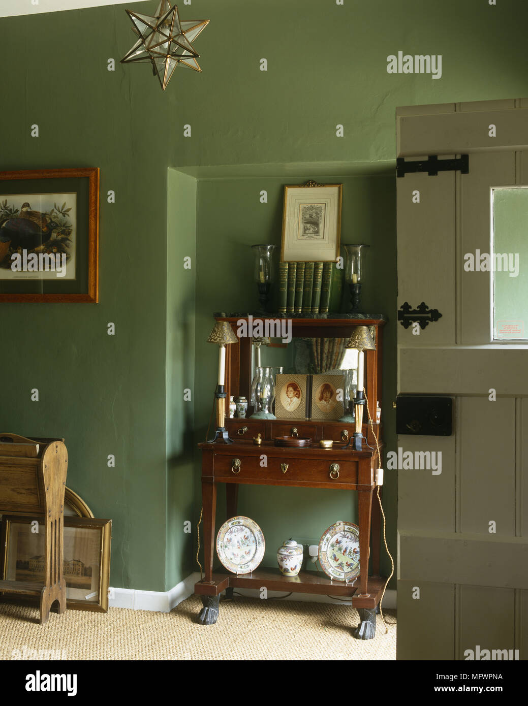 Frame Gestaltungsarbeit auf grüne Wand über Holz- seite Cabinet mit Ornamenten nebenan zu öffnen montiert Stockfoto