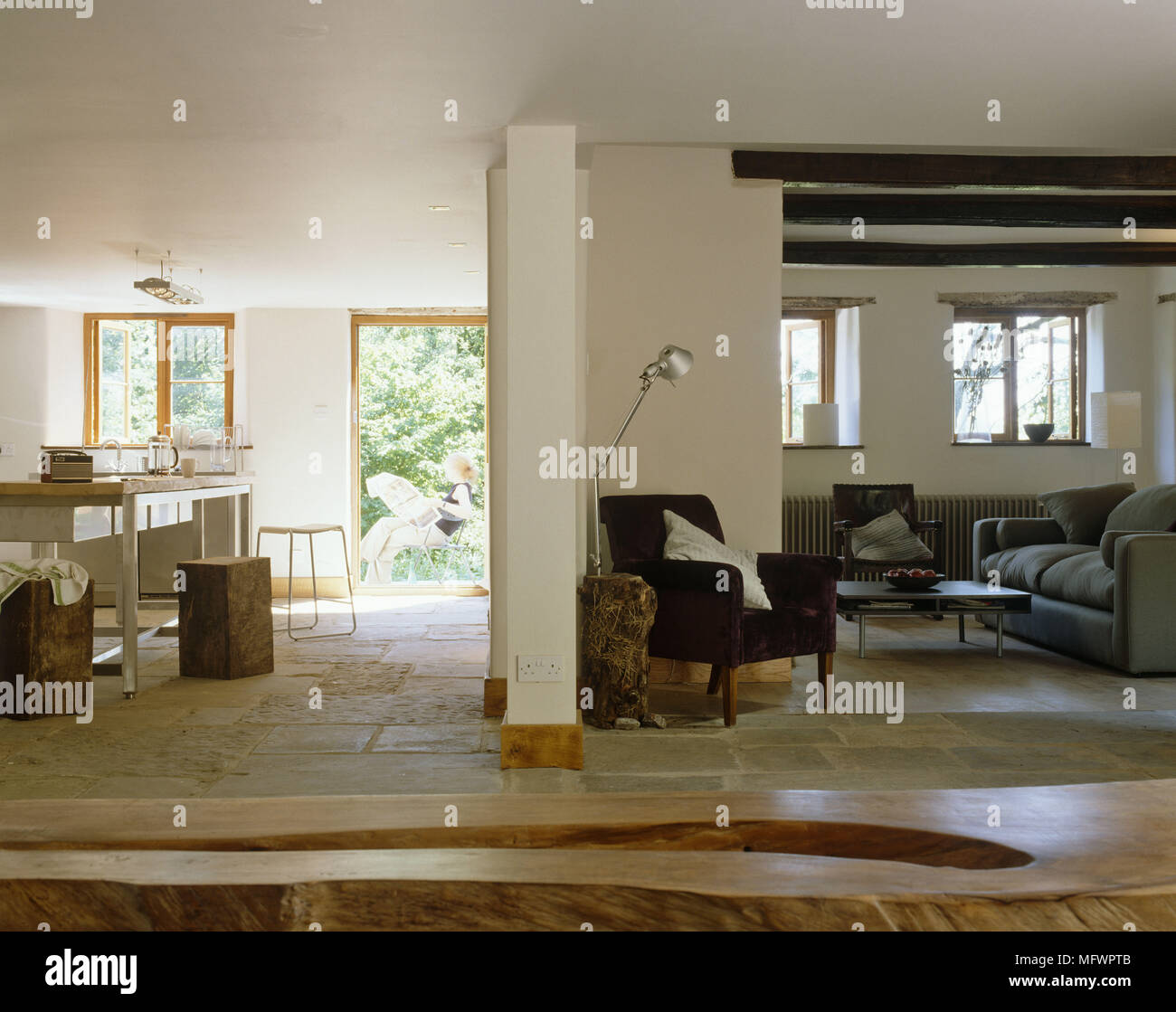 Holzbank vor Wohnzimmer mit Holzbalken und neben dem Essbereich mit Steinplatten Boden Stockfoto