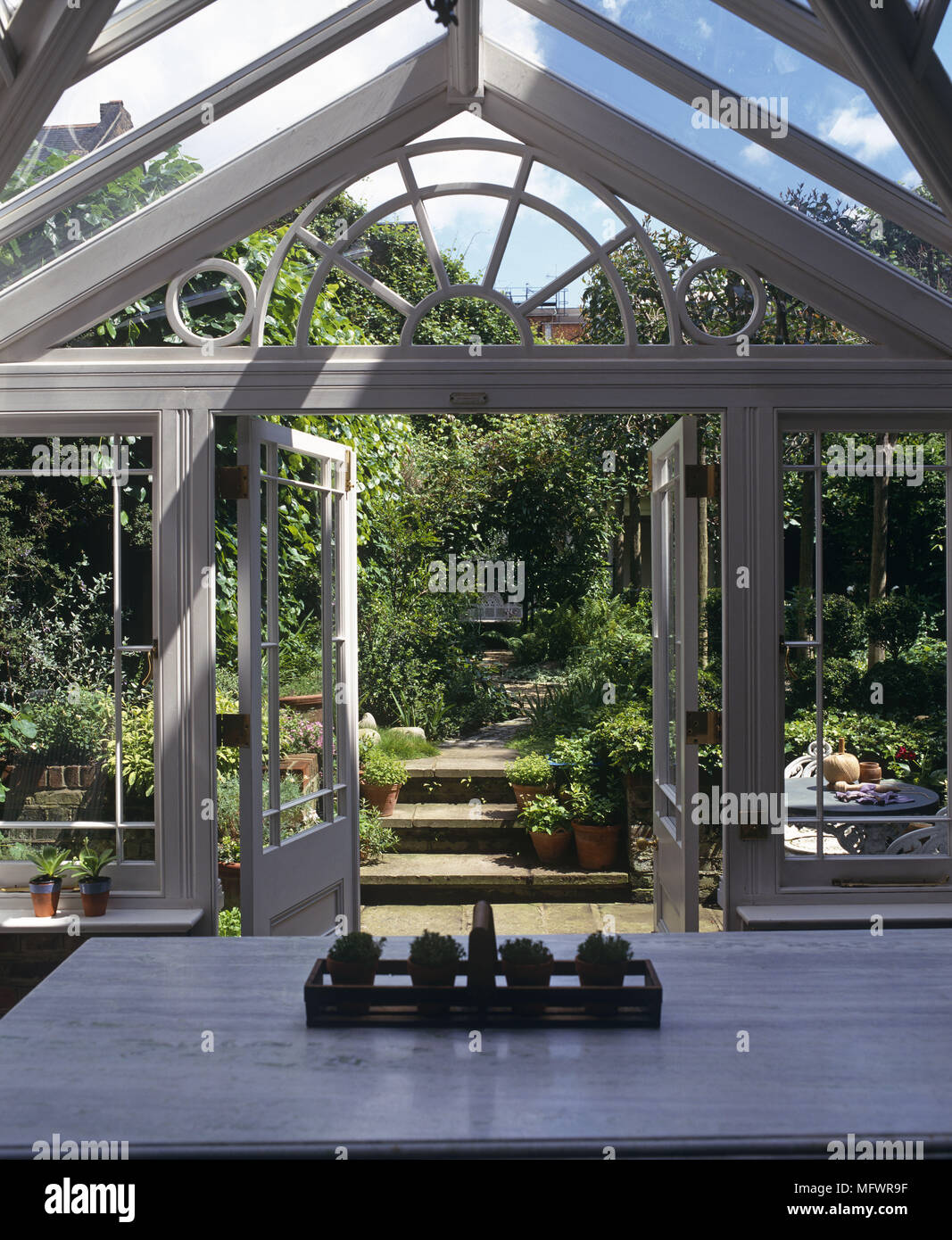 Tabelle vor der geöffneten Fenstertüren mit Blick auf den Garten Stockfoto