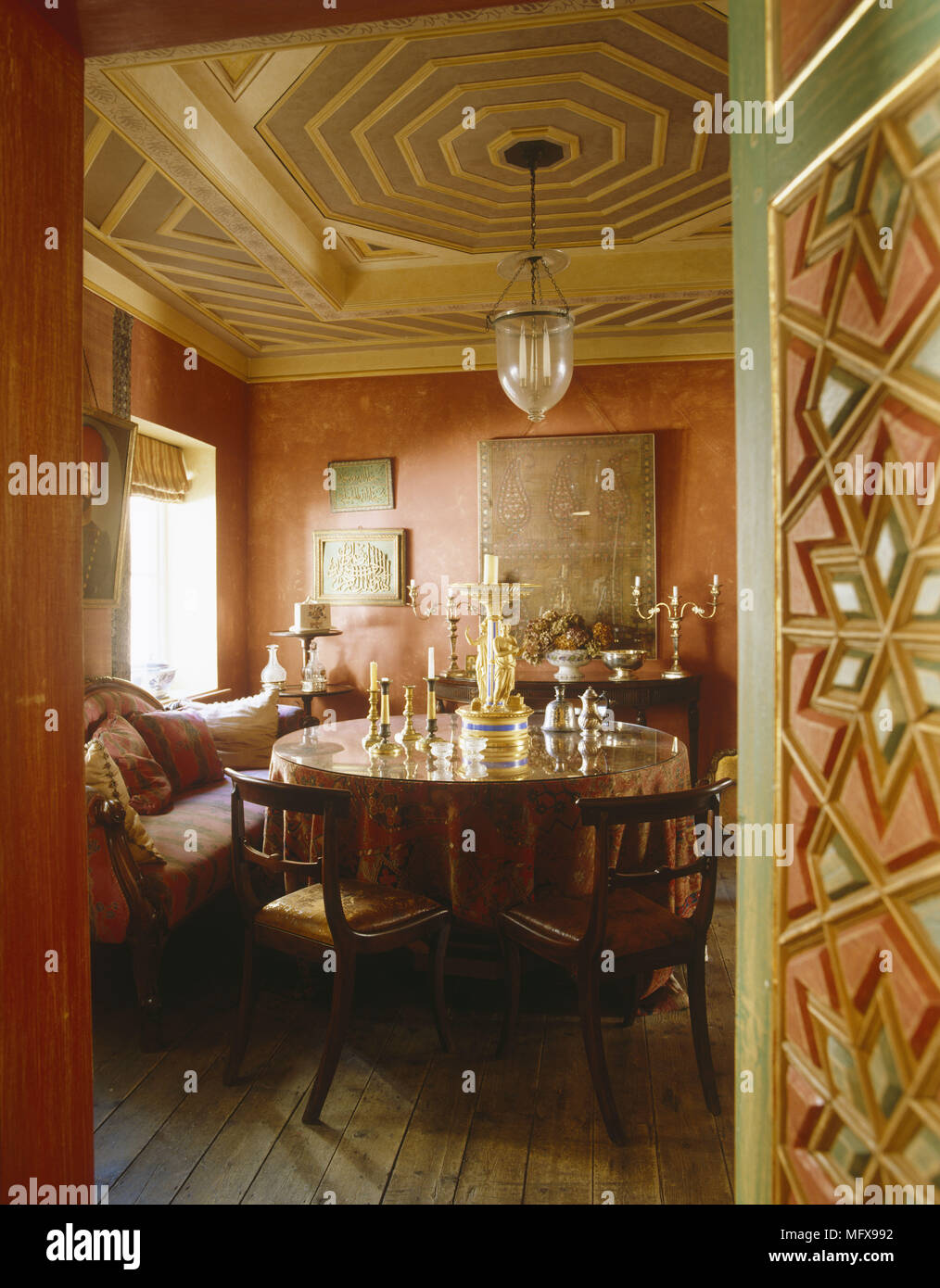 Blick durch die offene Tür zum Runden Tisch und Stühle in Terrakotta Esszimmer Stockfoto