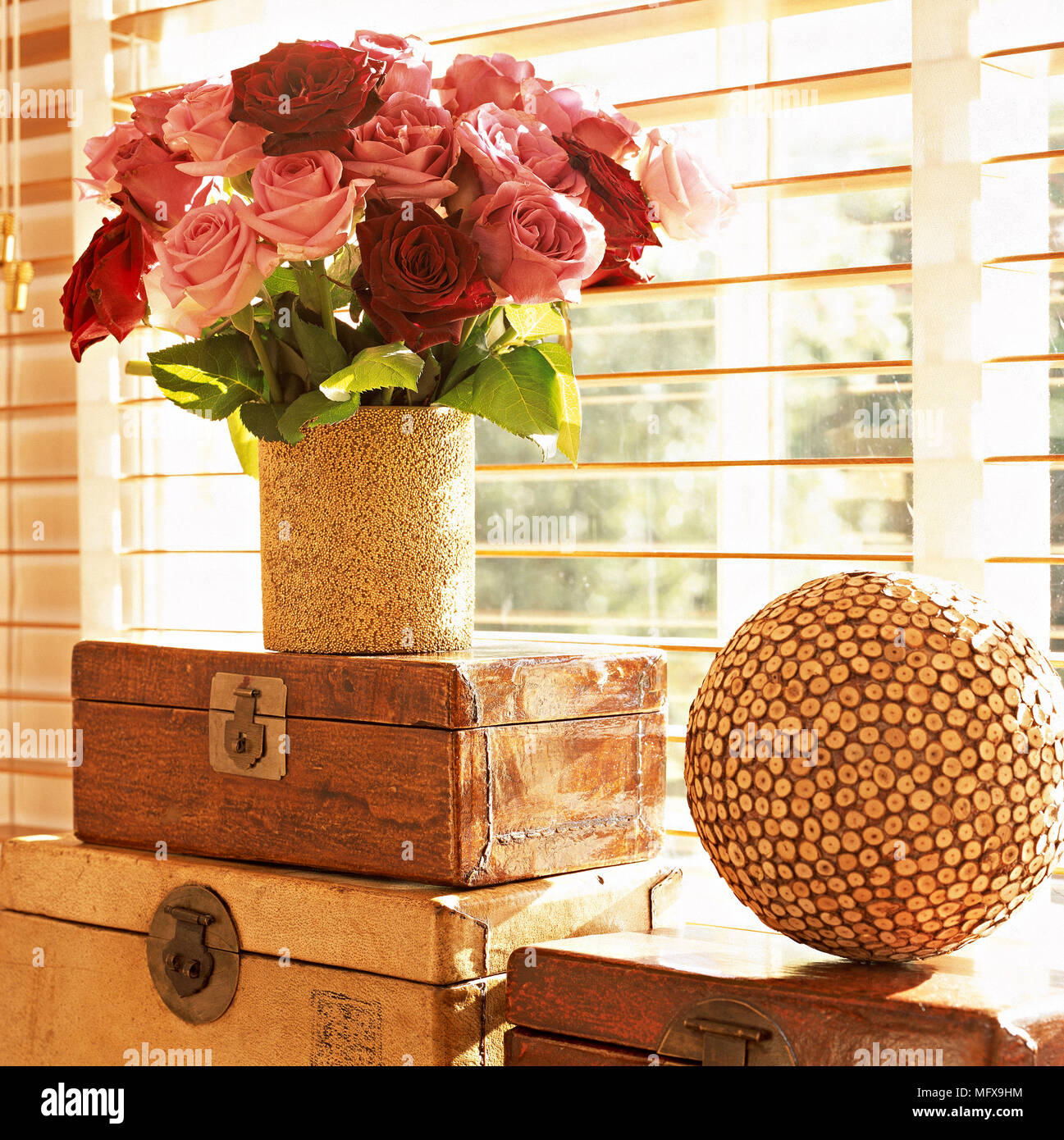 Ein Detail einer Blume Anordnung der roten und rosa Rosen in Vase, drei Holzkisten, sphärischen Ornament, Lattenrost blind, Fenster, Stockfoto